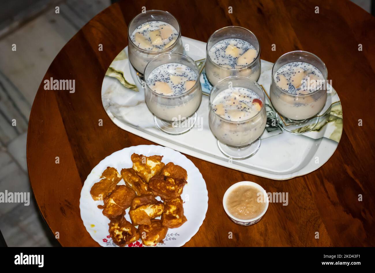 Apfelshake serviert mit indischem Hüttenkäse Pakoda am Couchtisch für die Heimparty Stockfoto