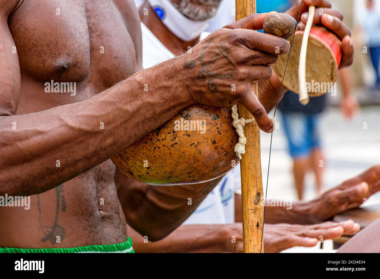 Afroamerikanischer Musiker, der während einer Capoeira-Performance auf den Straßen von Pelour ein traditionelles brasilianisches Schlagzeuginstrument namens Berimbau spielt Stockfoto