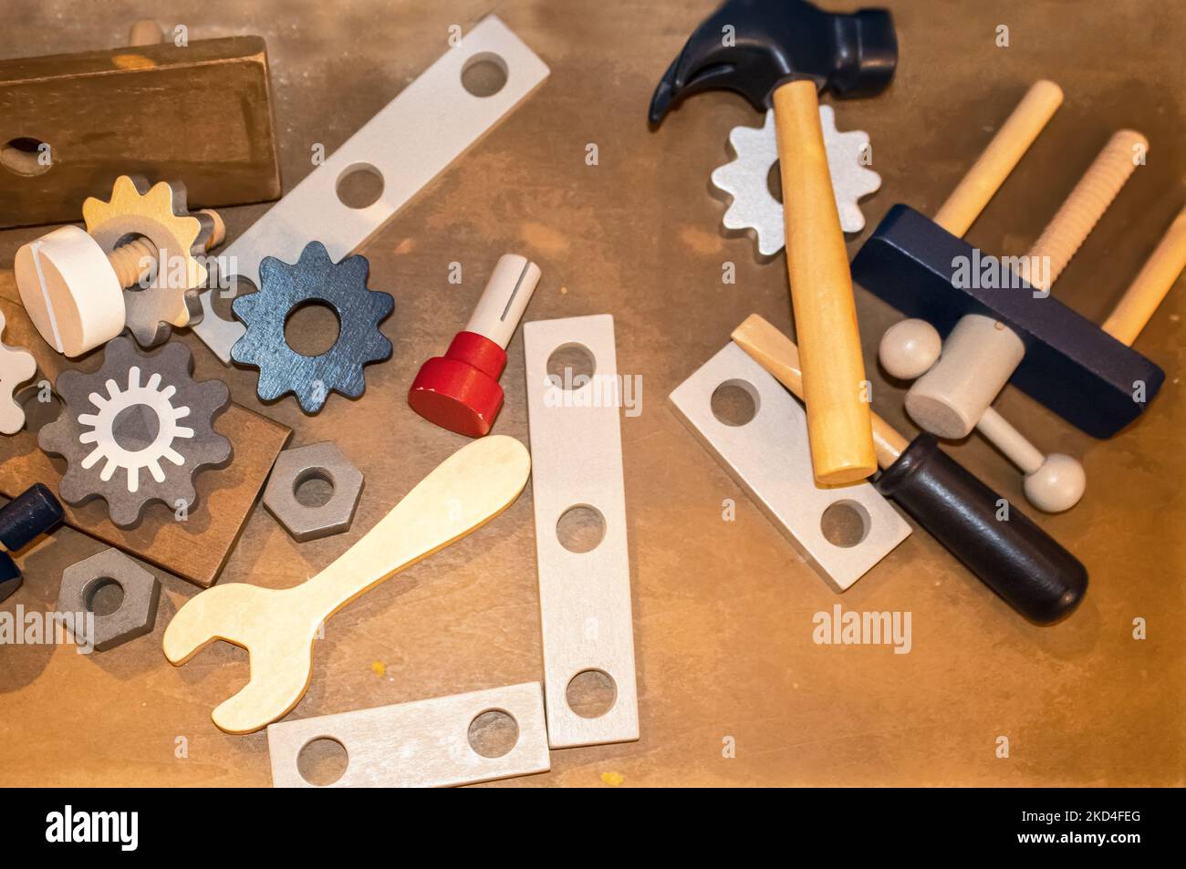 Spielzeug Holzspielzeug Werkzeuge einschließlich Zahnräder und ein Schraubenschlüssel und Hammer auf einer hölzernen Oberfläche verstreut - oben legen Stockfoto