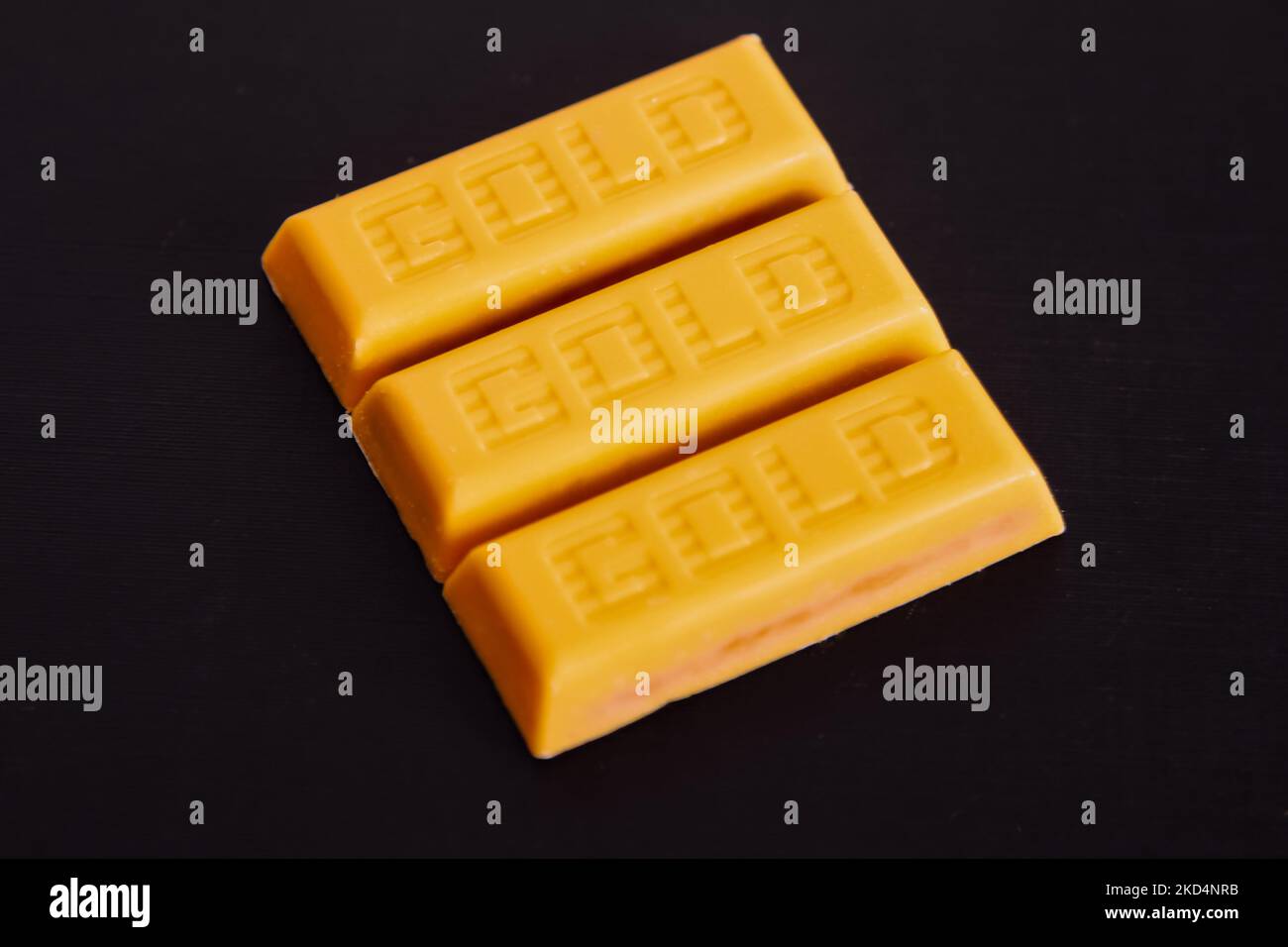 Unwrapped McVities Gold Bars – Snack-Leckereien aus goldener Schokolade ohne Verpackung auf schwarzem Hintergrund Stockfoto