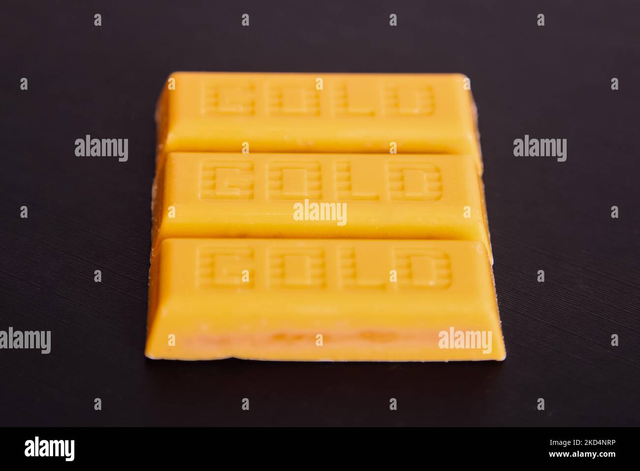 Unwrapped McVities Gold Bars – Snack-Leckereien aus goldener Schokolade ohne Verpackung auf schwarzem Hintergrund Stockfoto