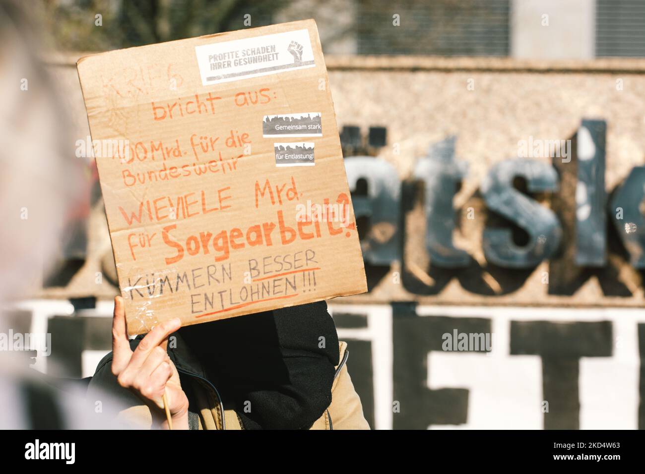 Ein Protestler hält am 11. März 2022 vor dem Kölner Universitätsklinikum ein Zeichen „ 100 Milliarden für die Bundeswehr, wie viele Milliarden für die Pflegearbeit“ (Foto: Ying Tang/NurPhoto) Stockfoto