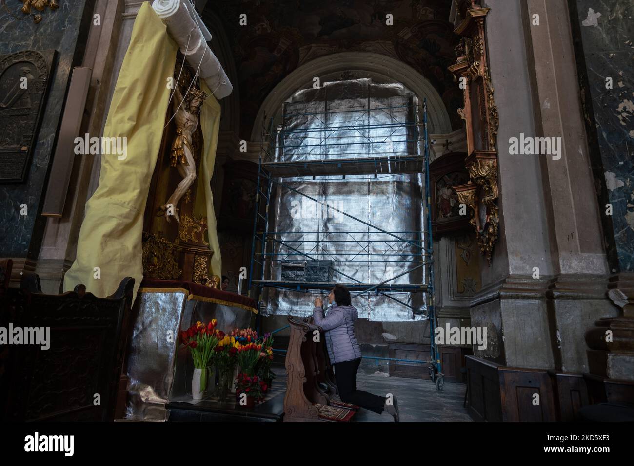 Am 23. März 2022 betet eine Frau in der Kirche der Heiligsten Apostel Petrus und Paulus in Lviv, Ukraine. Die Kirche aus dem 17.. Jahrhundert unternimmt Schritte, um ihre Kunstwerke zu schützen, inmitten der Angst, dass sie durch den russischen Krieg in der Ukraine beeinflusst werden könnte. Die Kirche wurde bereits während des Zweiten Weltkriegs im Jahr 1944 beschädigt. (Foto von Jordan Stern/NurPhoto) Stockfoto