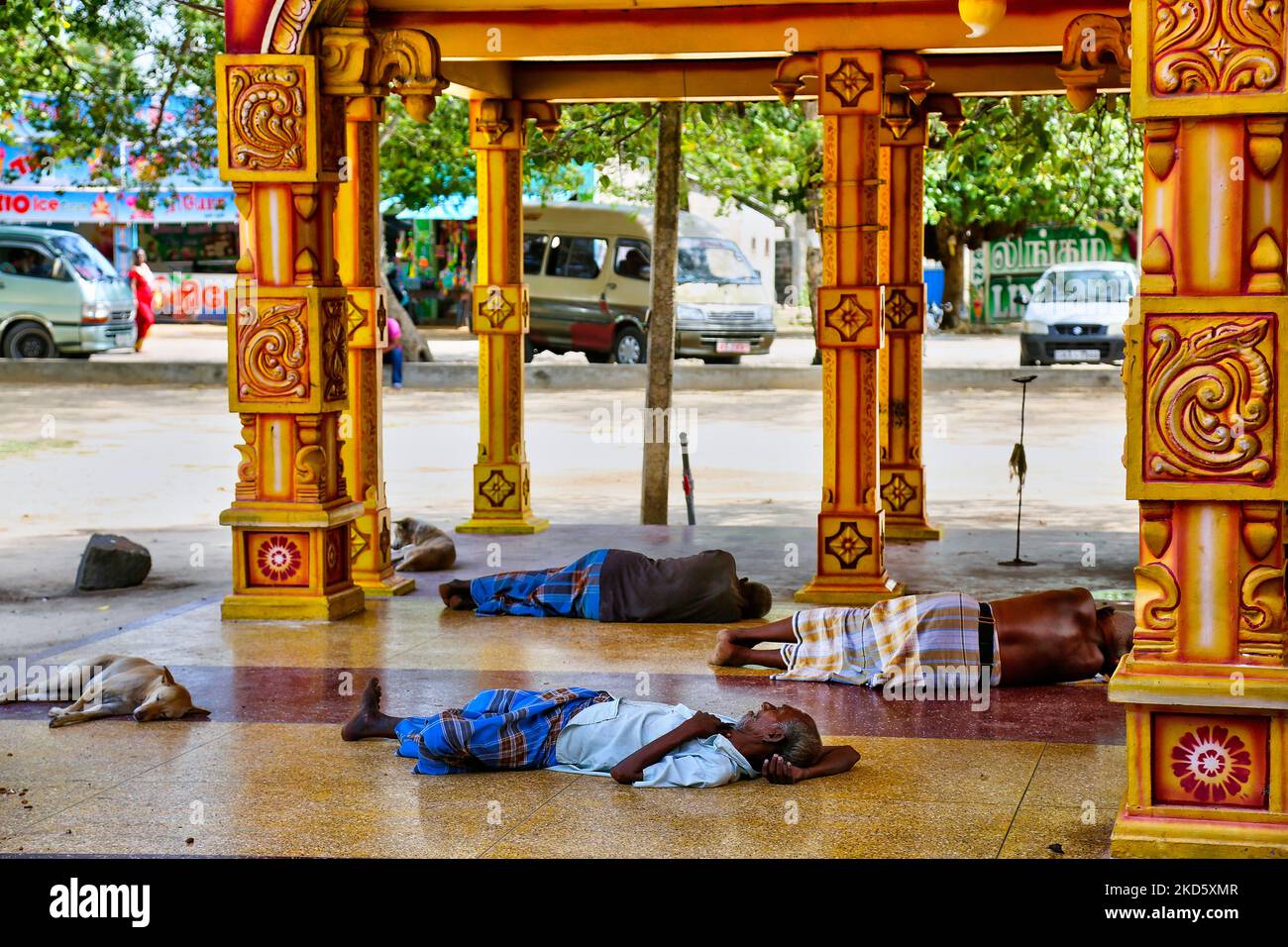 Ältere Männer schlafen vor dem Eingang zum Selva Sannidhi Murugan Tempel (Selvachannithy Murugan Kovil), während sie Zuflucht vor der heißen Mittagssonne in Thondaimanaru, Jaffna, Sri Lanka nehmen. Der Tempelkomplex ist Lord Murugan gewidmet und wurde nach der Geschichte von den Buddhisten angegriffen, die den Tempel und seine hölzernen Wagen zu Boden verbrannten. Um den Tempel herum wachsen große banyan-Bäume, die von Buddhisten Sri Lankas gepflanzt wurden. (Foto von Creative Touch Imaging Ltd./NurPhoto) Stockfoto