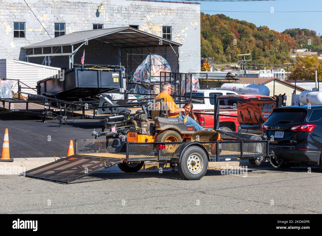 GALAX, VIRGINIA, USA-15 OCTOBER 2022: Mann entfernt den fahrenden Rasenmäher vom Anhänger, während Frau zuschaut. Stockfoto