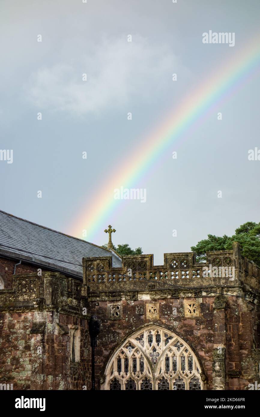 Detail einer Kirche mit Regenbogen vor einem dunklen, wolkigen Himmel Stockfoto