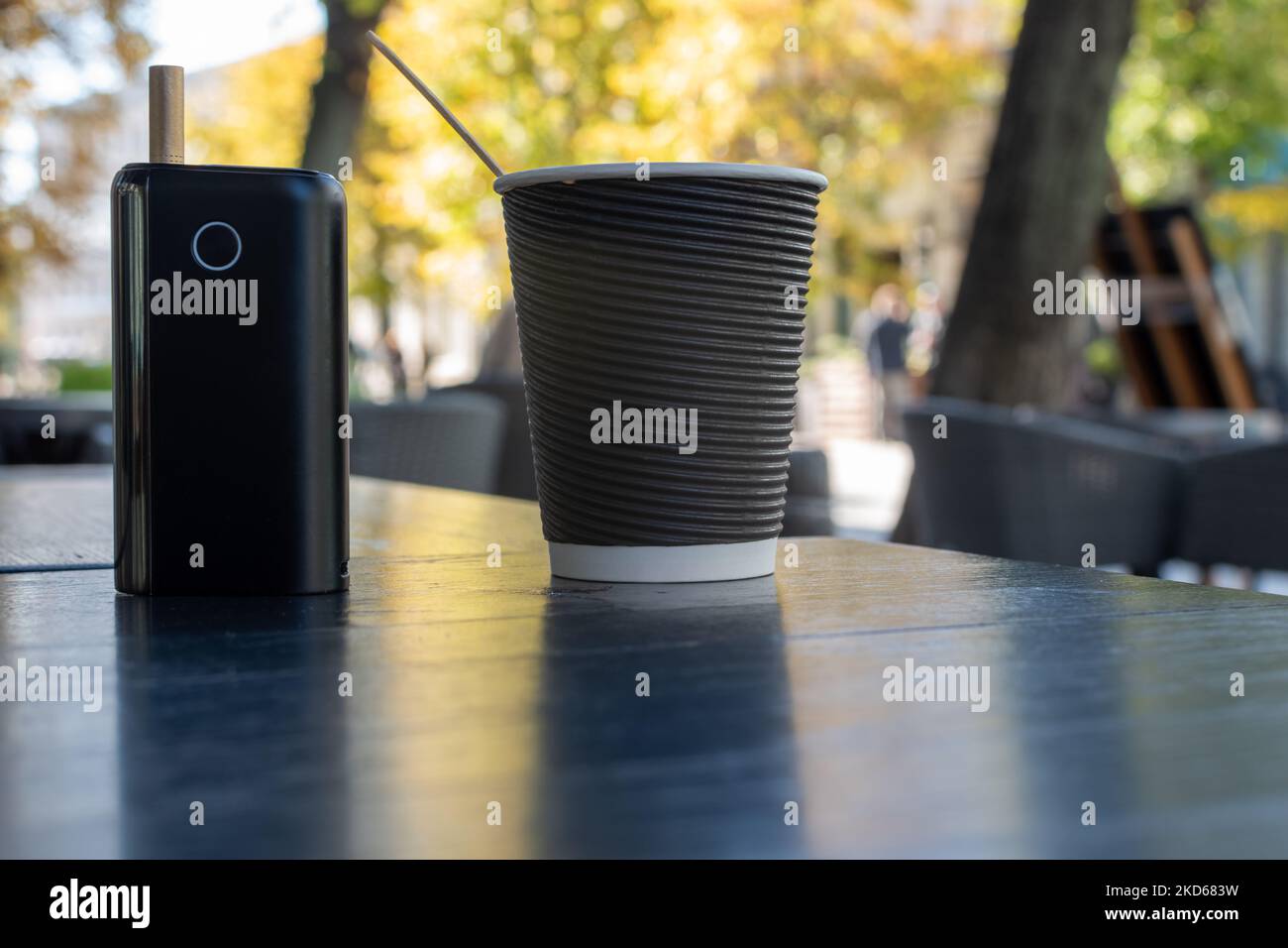 Gadget für die Verwendung von Tabakerzeugnissen und Papiertasse Kaffee auf dem Tisch des Straßencafés Stockfoto