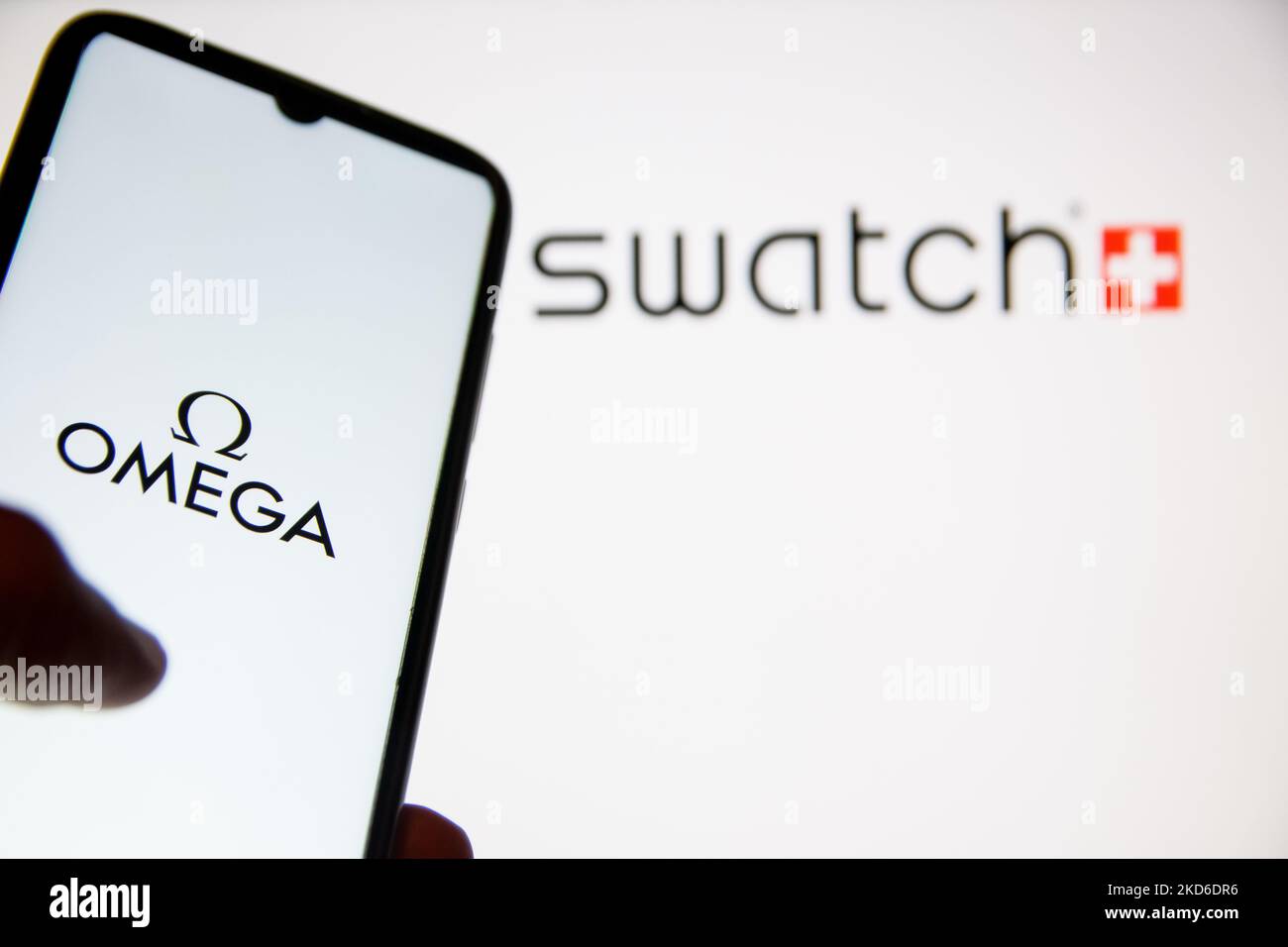 In dieser Abbildung wird am 31. März 2022 in Athen, Griechenland, ein Omega-Logo auf einem Smartphone-Bildschirm mit einem Swatch-Logo im Hintergrund angezeigt. Die Omega x Swatch Kollaboration ist eine Kollektion von vom Sonnensystem inspirierten Uhren, die auf der Omega Moonwatch basieren, der ersten Armbanduhr, die auf dem Mond getragen wird, aber für einen Bruchteil des Preises erhältlich ist. (Foto von Nikolas Kokovlis/NurPhoto) Stockfoto