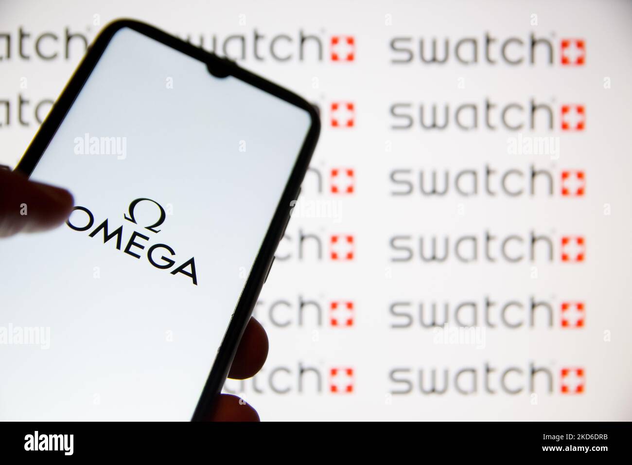 In dieser Abbildung wird am 31. März 2022 in Athen, Griechenland, ein Omega-Logo auf einem Smartphone-Bildschirm mit einem Swatch-Logo im Hintergrund angezeigt. Die Omega x Swatch Kollaboration ist eine Kollektion von vom Sonnensystem inspirierten Uhren, die auf der Omega Moonwatch basieren, der ersten Armbanduhr, die auf dem Mond getragen wird, aber für einen Bruchteil des Preises erhältlich ist. (Foto von Nikolas Kokovlis/NurPhoto) Stockfoto