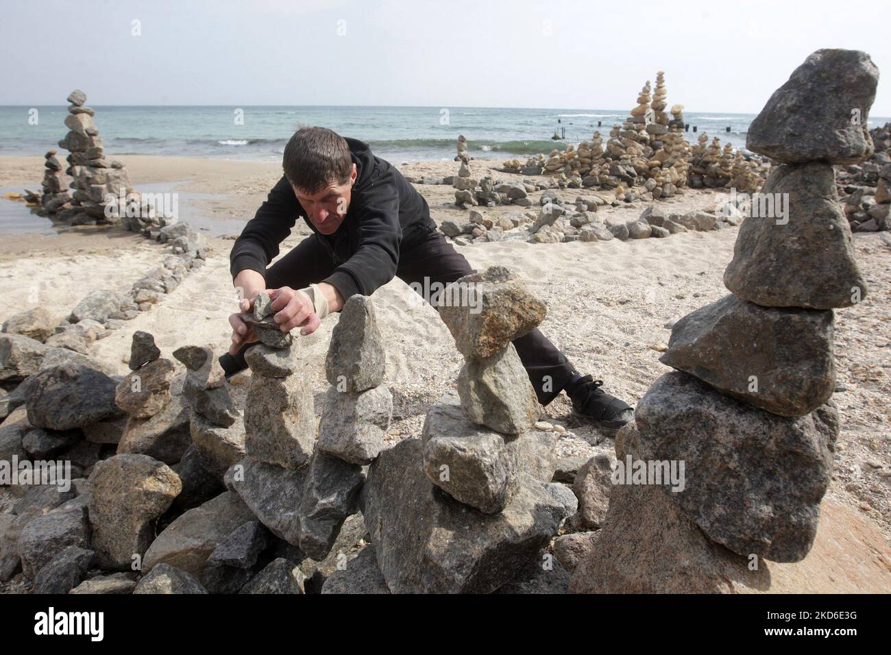 Alexander Izman (49 Jahre alt) schafft ein improvisiertes Kunstobjekt aus Steinen namens Rock Garden am Strand der Stadt Odesa, Ukraine. Der örtliche Alexander Izman kommt zwei Jahre lang an den Strand von Odesa, um Steinskulpturen zu schaffen. Einige der Steine wiegen bis zu 30 kg. Es ist ziemlich schwierig, die Konfiguration, Form, Gewicht und das Gleichgewicht der Steine zu wählen, aber die Energie hat sich hier verändert und einige Leute kommen und meditieren hier, sagt er. (Foto von STR/NurPhoto) Stockfoto