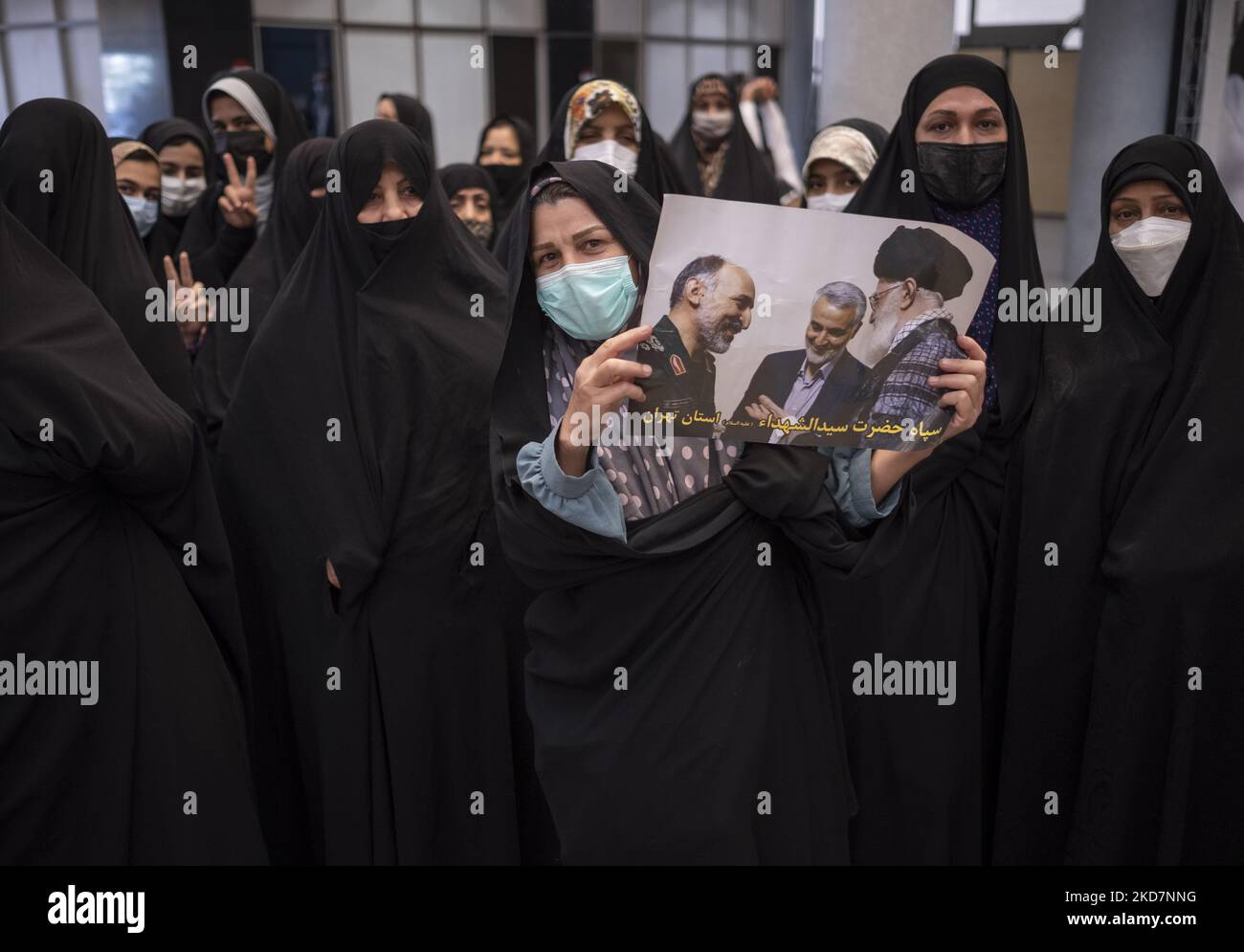 Verschleierte Frauen blinken Siegeszeichen, während eine von ihnen ein Plakat mit Porträts des iranischen Obersten Führers Ayatollah Ali Khamenei (R), des ehemaligen Kommandeurs der Quds-Streitkräfte Qasem Soleimani (C) des IRGC und des ehemaligen Kommandeurs der paramilitärischen Streitkräfte der Basidsch, Mohammad Hossein-Zadeh Hejazi, hält. Nach einer Zeremonie im Gebäude des iranischen Innenministeriums in der Innenstadt von Teheran am 14. April 2022. (Foto von Morteza Nikoubazl/NurPhoto) Stockfoto