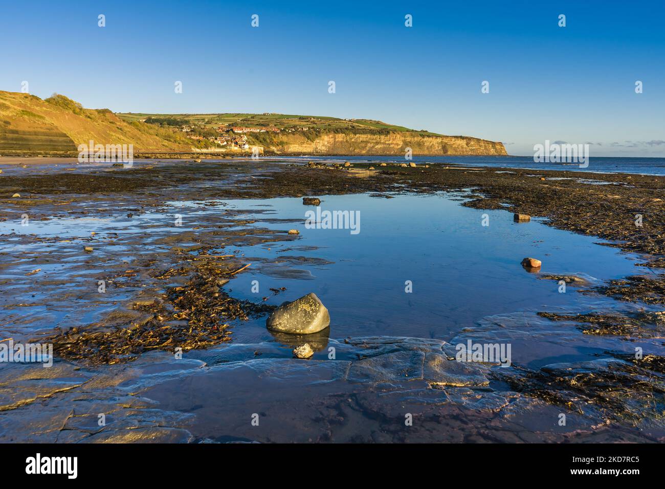 Blick entlang des Strandes in Richtung Robin Hoods Bay von Boggle Hole. Es ist früh am Morgen und Ebbe, die felsige Regale und Pools freilegt. Stockfoto