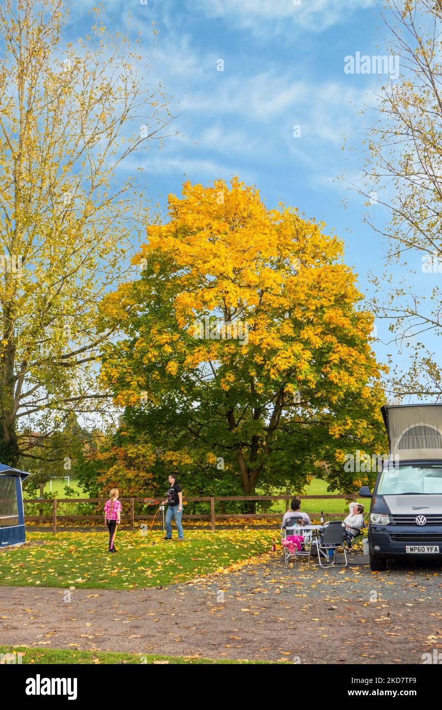 Familie, die die Herbstsonne genießt und draußen Spiele spielt, während sie in ihrem Wohnmobil auf dem Wolverley Camping and Caravan Club-Gelände in Worcestershire zeltet Stockfoto