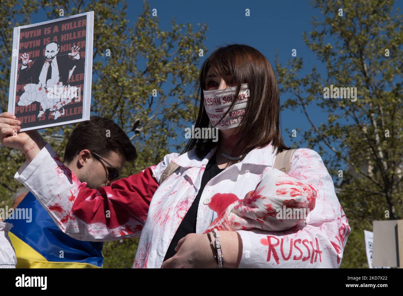 Ein Protestler trägt blutrote Kleider, hält eine Puppe, die ein ermordtes Kleinkind symbolisiert, in ihren Armen und zeigt ein Zeichen dafür, dass Putin die Ukraine in Paris am 16. April 2022 verschlingt. (Foto von Andrea Savorani Neri/NurPhoto) Stockfoto