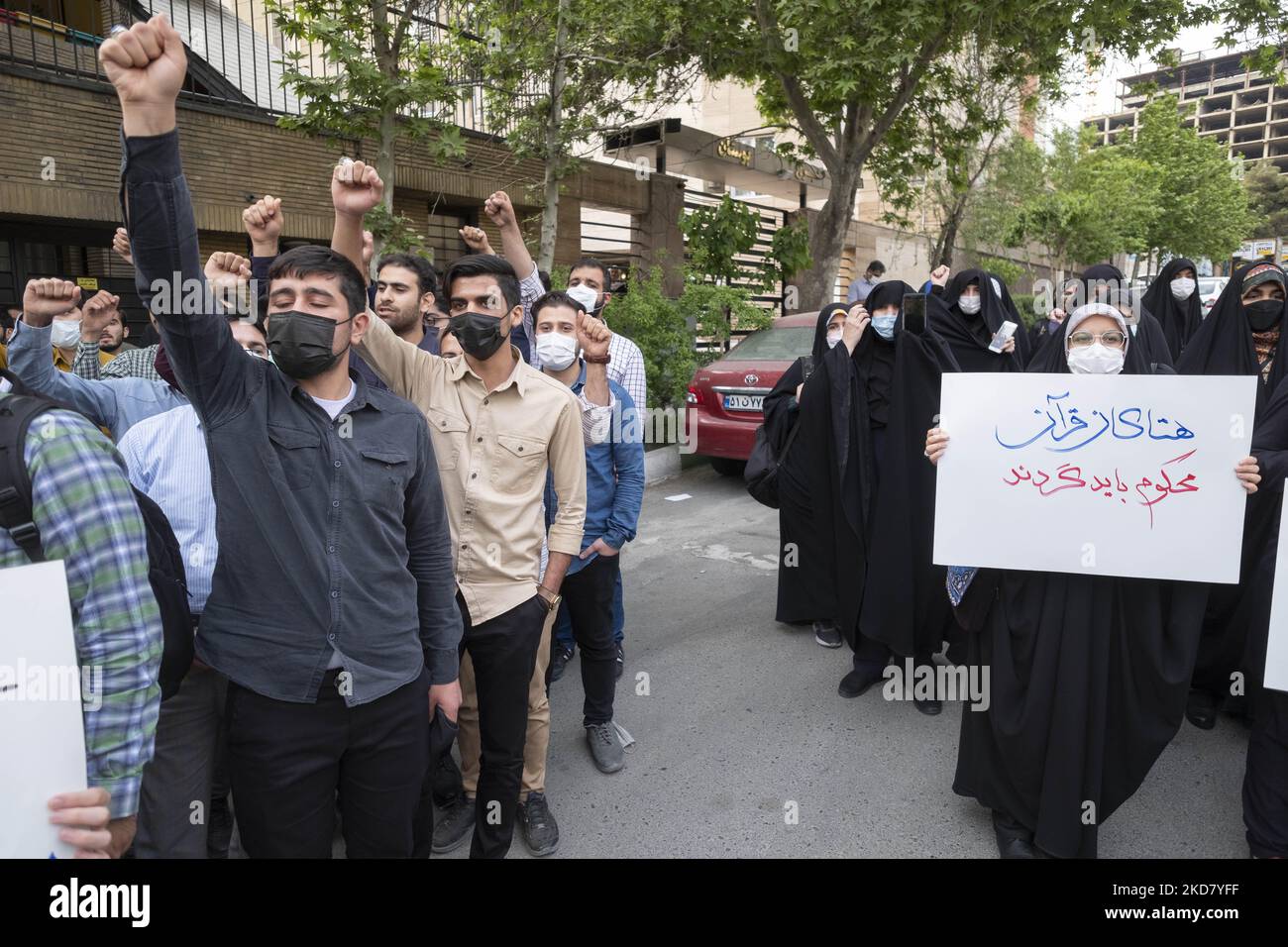 Eine Gruppe iranischer Männer ruft Slogans, um die Koranverbrennung in Schweden zu verurteilen, während eine verschleierte Frau ein Plakat mit persischer Schrift hält, auf dem der Koran verurteilt werden sollte, während einer Protestveranstaltung vor der schwedischen Botschaft im Norden Teherans am 18. April 2022. (Foto von Morteza Nikoubazl/NurPhoto) Stockfoto