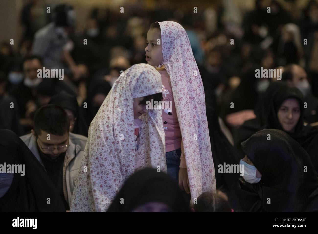 Zwei iranische verschleierte junge Mädchen stehen neben ihrer Mutter, während sie während der ersten Nacht des Qadr-Massengebets, zwei Jahre nach dem Ausbruch der neuen Coronavirus-Krankheit (COVID-19) im Iran, am 20. April 2022, die große Moschee des Imam Khomeini in der Innenstadt von Teheran besuchen. (Foto von Morteza Nikoubazl/NurPhoto) Stockfoto
