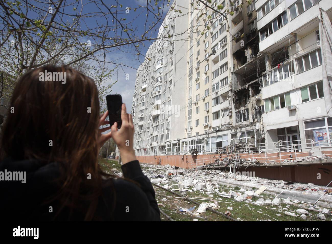 Eine Frau fotografiert ein Wohnhaus, das am 24. April 2022 von einem Raketenangriff in Odesa, Ukraine, getroffen wurde. Am 23. April berichteten ukrainische Beamte, dass Russland sechs Raketen auf Odesa abgefeuert habe und dabei mindestens acht Menschen, darunter ein Baby, getötet habe. (Foto von STR/NurPhoto) Stockfoto