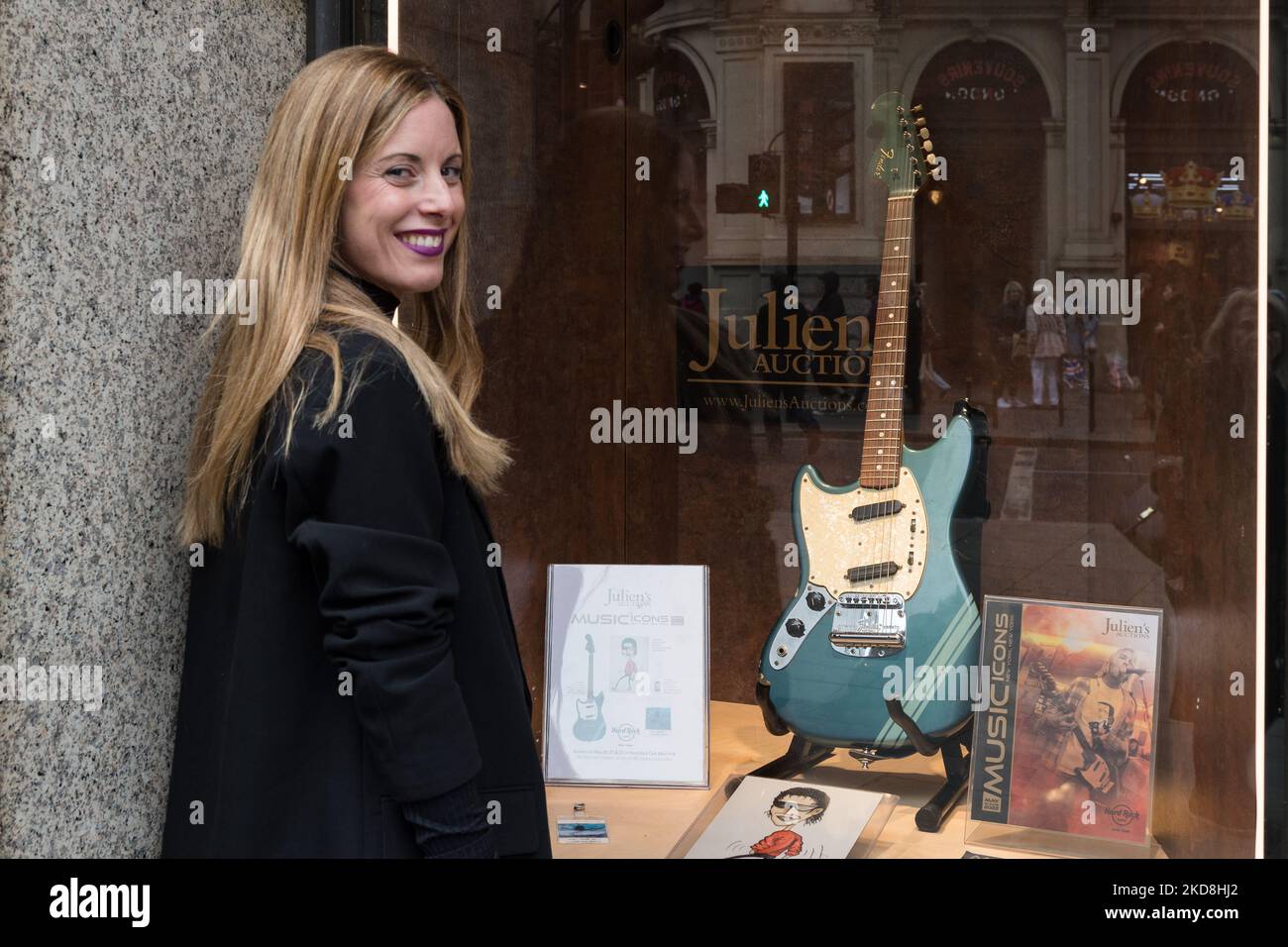 LONDON, GROSSBRITANNIEN - 27. APRIL 2022: Eine Frau lächelt neben der Fender Mustang E-Gitarre, Linkshänder im Competition Lake Placid Blue Finish mit passendem Kopfteil (1969), Startschätzung: $600.000 - 800.000 US-Dollar, gespielt von Kurt Cobain in Nirvanas ikonischem Musikvideo „Smells Like Teen Spirit“, zusammen mit anderen Artefakten, die mit Kurt Cobain zu tun haben, werden am 27. April 2022 im Hard Rock Cafe Piccadilly Circus in London, England, gezeigt. Die Erinnerungsstücke werden von Julien’s Auctions während DER DREITÄGIGEN Auktion VON MUSIC ICONS angeboten, die zwischen dem 20.. Und 22.. Mai im Hard Rock Cafe in stattfindet Stockfoto