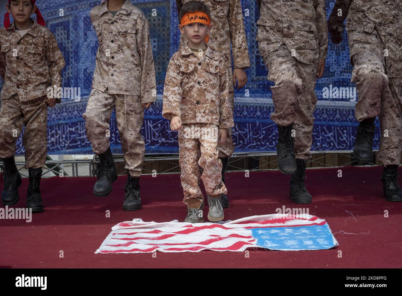 Ein iranischer Schuljunge, der eine Militäruniform des Islamic Revolutionary Guard Corps (IRGC) trägt, steht auf der US-Flagge, während er während einer Kundgebung zum Gedenken an den Internationalen Quds-Tag, der auch als Jerusalemtag bekannt ist, in der Innenstadt von Teheran am 29. April 2022 auftrat. (Foto von Morteza Nikoubazl/NurPhoto) Stockfoto