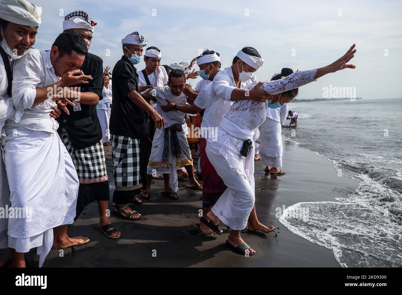 Balinesische Hindu-Frau weint während der Melasti, einer Reinigungszeremonie vor Nyepi am Padang Galak Strand in Denpasar, Bali, Indonesien, während sie sich in Trance befindet, am 28. Februar 2022. Das Melasti-Ritual findet jährlich vor dem Nyepi-Tag der Stille statt, einer Zeremonie, die die Seelen der balinesischen Hindu-Teilnehmer reinigen und reinigen soll. Nyepi ist eine hinduistische Feier, die jedes neue Jahr nach dem balinesischen Kalender gefeiert wird. Der Nationalfeiertag ist ein Feiertag der Selbstreflexion und Meditation und Aktivitäten wie Arbeiten, Fernsehen schauen, oder Reisen ist zwischen den Stunden von 6 Uhr und beschränkt Stockfoto