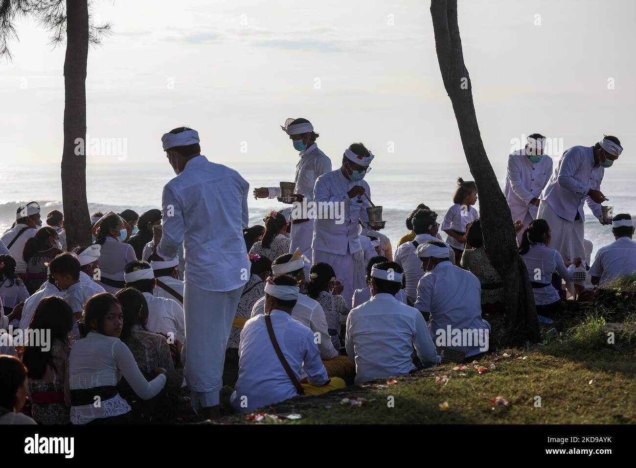 Balinesische Hindu-Anhänger erhalten heiliges Wasser, während sie während der Melasti beten, einer Reinigungszeremonie vor Nyepi an einem Strand in Bali, Indonesien, am 1. März 2022. Balinesische Hindus trugen in überwiegend weißer Kleidung heilige Bildnisse von Göttern und Göttinnen und rituelle Utensilien von ihren Dorftempeln zum Strand, um eine Reinigungszeremonie, das sogenannte Melasti-Ritual, durchzuführen. Balinesische Hindus glauben, dass das Melasti-Ritual vor dem Nyepi-Tag, dem Tag der Stille, ein muss ist, um die Seele und die Natur zu reinigen, die übernatürliche Kraft der heiligen Tempelobjekte aufzuladen und die te zu reinigen Stockfoto