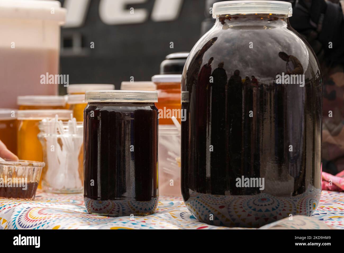 Zwei Gläser in verschiedenen Größen, gefüllt mit dunkelreifendem Bashkir-Bienenhonig. Es gibt Handel auf der Herbstlandwirtschaftsmesse. Stockfoto