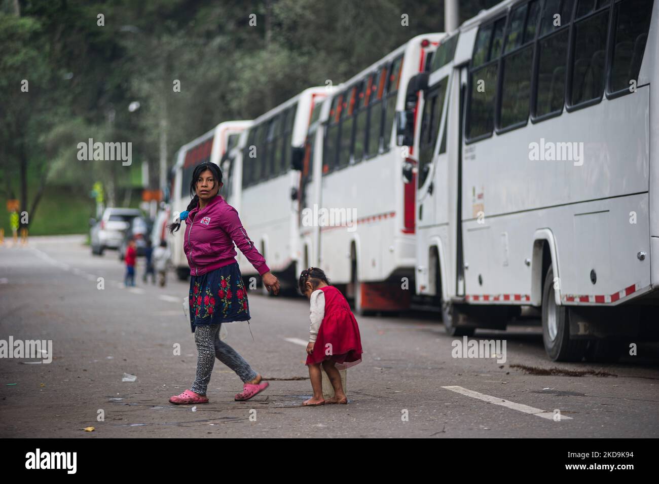 Eine indigene Mutter und ihr Kind gehen neben den Bussen, die die indigenen Gemeinden transportieren werden, während die indigenen Gemeinden der Embera das provisorische Lager verlassen, das vor 8 Monaten errichtet wurde, wo mehr als 1000 durch Konflikte vertriebene indigene Menschen lebten und Vereinbarungen mit der Regierung getroffen haben, in die sie verlegt werden sollen Ein Ort in der Nähe, bevor Sie in ihre Gebiete zurückkehren, in Bogota, Kolumbien 9. Mai 2022. (Foto von Sebastian Barros/NurPhoto) Stockfoto