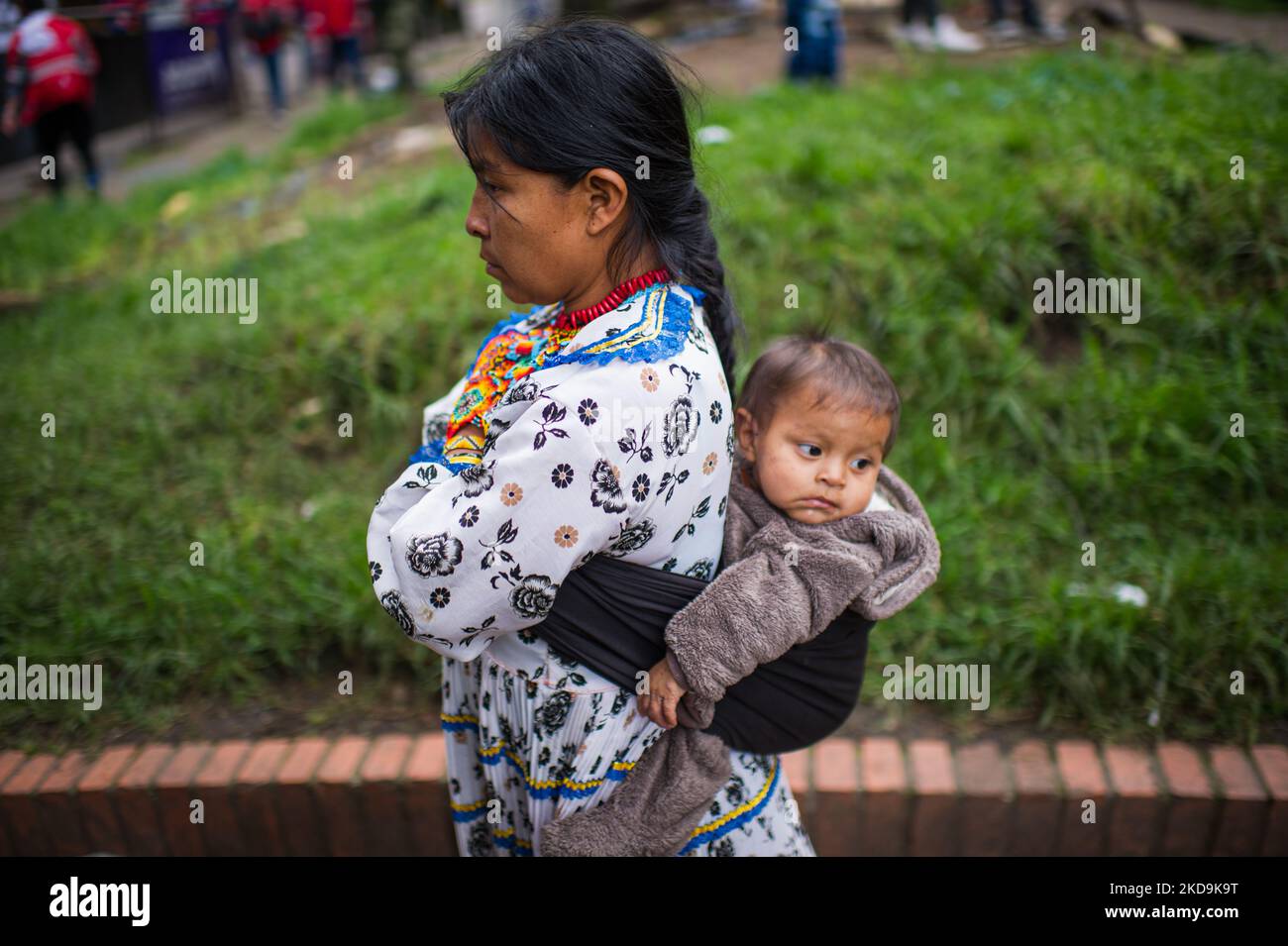 Eine indigene Mutter trägt ihr Baby auf dem Rücken, als die indigenen Gemeinden der Embera das provisorische Lager verlassen, das vor 8 Monaten errichtet wurde, wo mehr als 1000 durch Konflikte vertriebene indigene Menschen lebten und Vereinbarungen mit der Regierung getroffen haben, an einen nahe gelegenen Ort zu überführen, bevor sie in ihre Territorien zurückkehren. In Bogota, Kolumbien, 9. Mai 2022. (Foto von Sebastian Barros/NurPhoto) Stockfoto