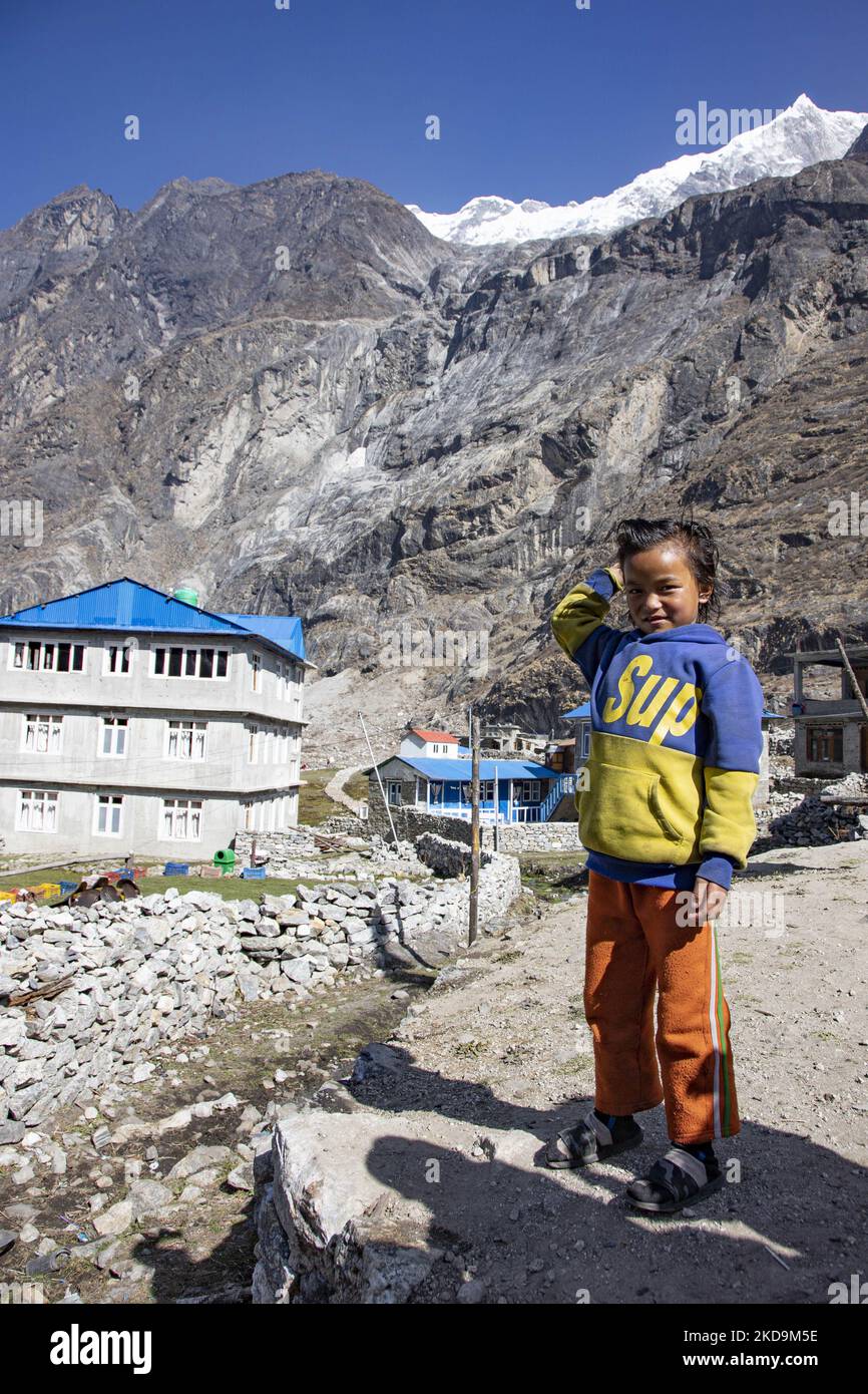 Schüler, Schüler, wie sie außerhalb der örtlichen Schule unter dem Langtang Lirung Peak gesehen werden. Langtang Lirung Peak aus Sicht des Dorfes Langtang, Teil des Langtang Himal Berges in Nepal mit dem höchsten Punkt in einer Höhe von 7234m oder 23734 Fuß. Der Langtang Lirung ist der 99. höchste Berg der Welt und wurde 1978 zum ersten Mal erreicht. Am 25. April 2015 führte ein massives Erdbeben der Stärke 7,8 zu einer Lawine und einem Erdrutsch im Dorf Langtang, bei dem direkt 243 Menschen getötet und das Dorf verschwungen wurden. Der Langtang National Park ist ein beliebtes Trekking- und Reiseland für Fore Stockfoto