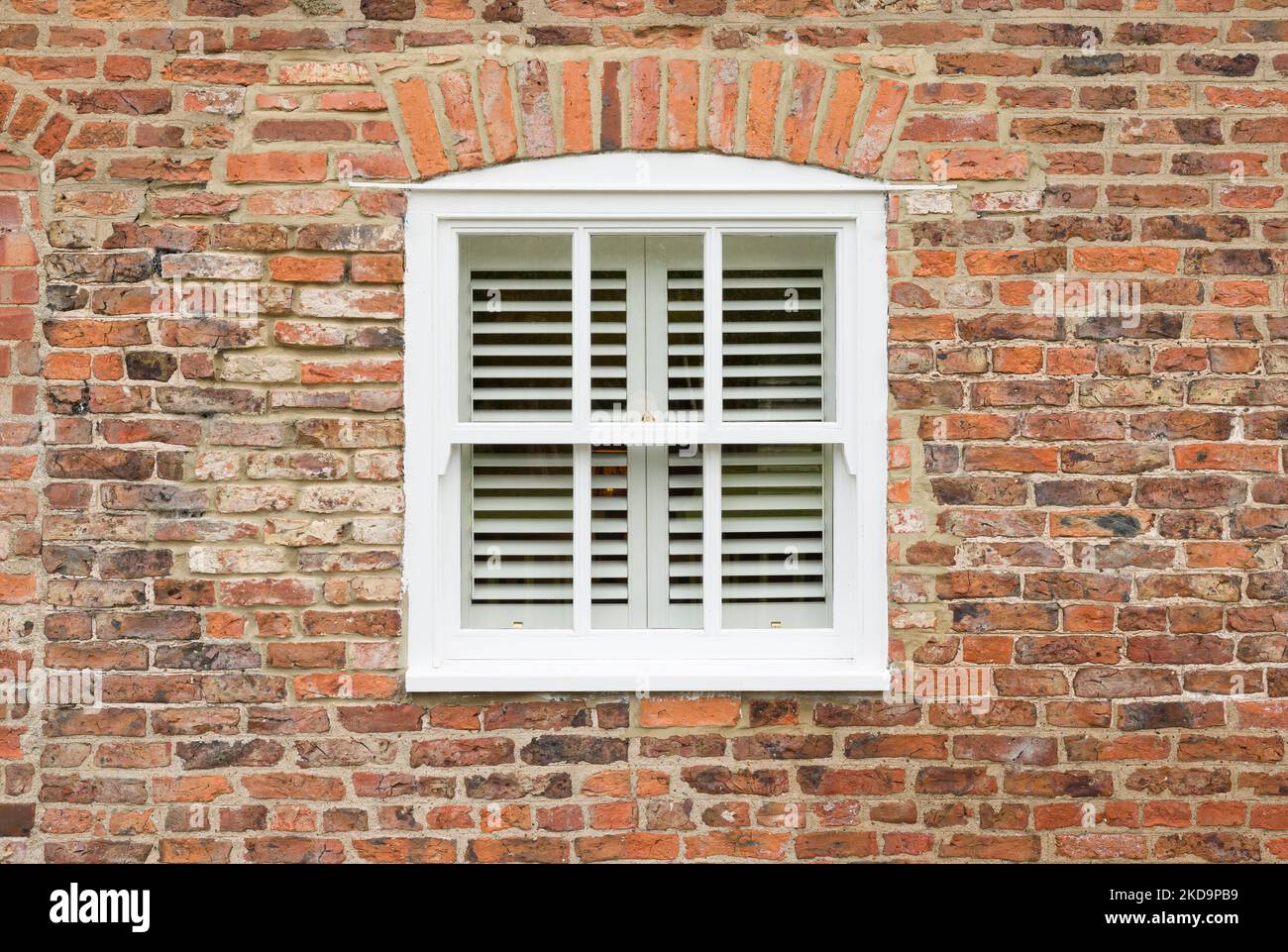 Außenansicht eines alten Backsteinhauses mit Holzfenster und Holzjalousien, England, Großbritannien Stockfoto