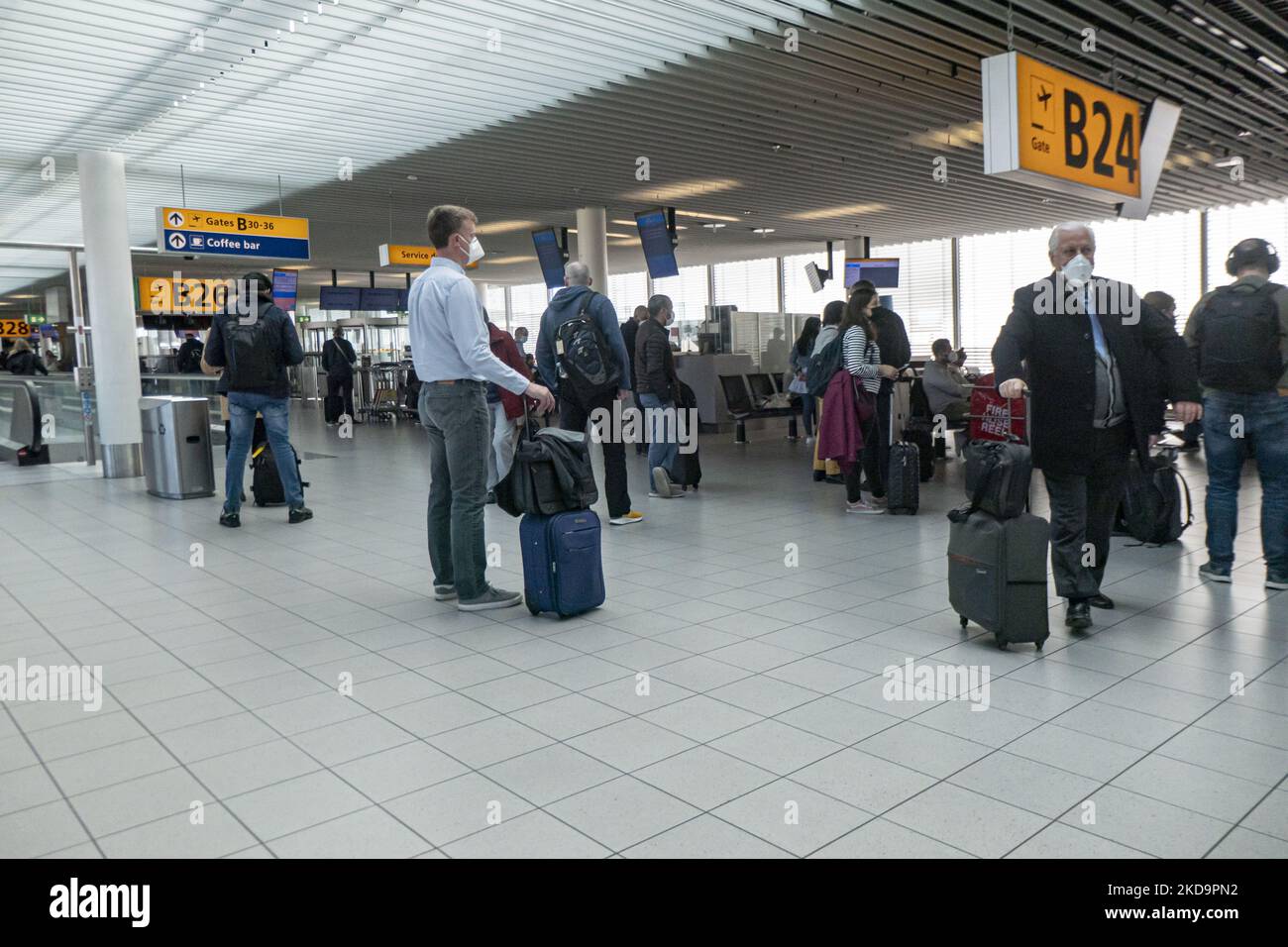 Passagiere, die Gesichtsmasken im Terminal, in der Abflughalle und im Abflugbereich des Flughafens Amsterdam Schiphol tragen, sehen AMS EHAM vor ihrem Abflug aufgrund von Covid-19-Pandemiemaßnahmen, während auf Transparenten im Flughafen die Verwendung der Maske angezeigt wird. Ab dem 16. Mai 2022 werden für den Flugverkehr in Europa keine Gesichtsmasken mehr benötigt, wie die Europäische Agentur für Flugsicherheit EASA und das Europäische Zentrum für die Prävention und die Kontrolle von Krankheiten ECDC angekündigt haben. Die Regel einer obligatorischen Gesichtsmask im Flugzeug ist in einigen Ländern bereits beendet, da viele die Maßnahmen und Beschränkungen aussetzen, um die SP zu verhindern Stockfoto