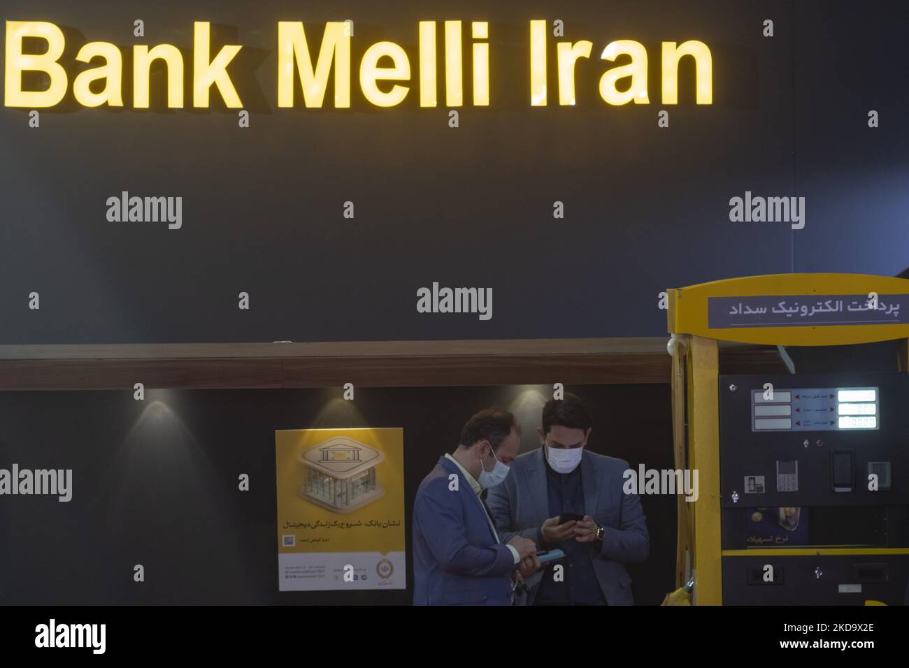 Zwei Jahre nach dem Ausbruch der COVID-19 im Iran nutzen zwei Mitarbeiter der Bank Melli Iran (BMI) ihre Handys, während sie am 13. Mai 2022 vor dem Stand des BMI auf der Internationalen Ausstellung für Öl, Gas, Raffinierung und Petrochemie 26. in Teheran stehen. (Foto von Morteza Nikoubazl/NurPhoto) Stockfoto