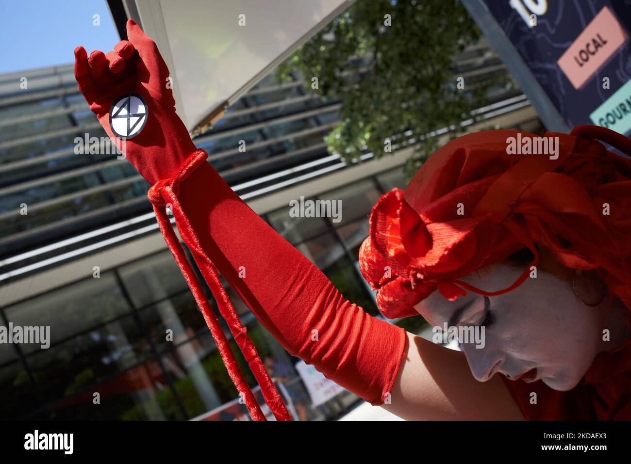 Eine in Rot gekleidete Protesterin, die die Dringlichkeit symbolisiert, gegen die Emissionen von wärmenden Gasen zu handeln, hebt ihre Hand mit dem Symbol von XR. XR France (Extinction Rebellion) und ANV-COP21 organisierten ein die-in, um gegen einen von der TSE (Toulouse School of Economics) organisierten Gipfel mit dem CEO von ExxonMobil Europe, dem CEO von AXA France, zu protestieren. Das Thema ist „grüne“ Energie (Wasserstoff, Erdgas) und die Eindämmung des Klimawandels. XR und ANV-COP21 prangern die Anwesenheit von ExxonMobil an (das mehrere „Klimabomben“ besitzt, wie von den Peers-Revue Energy Po definiert Stockfoto