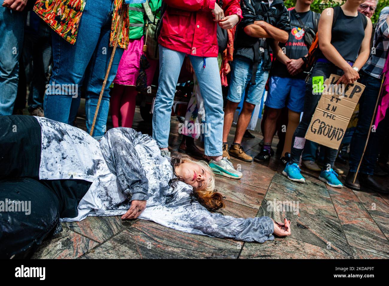 Während der von XR organisierten Demonstration gegen die fossile Industrie in Rotterdam am 19.. Mai 2022 liegt eine Frau auf dem Boden, deren Kleidung mit gefälschtem schwarzem Öl befleckt ist. (Foto von Romy Arroyo Fernandez/NurPhoto) Stockfoto