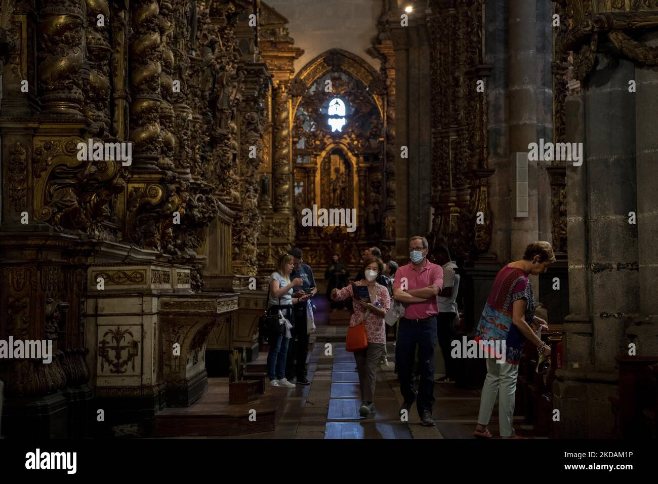 Man sieht Menschen, die entlang des Seitenkorridors in der Nähe des Denkmals der Jungfrau des Guten Todes in der Kirche von San Francisco spazieren gehen. Porto, 05. Mai 2022. Es ist eines der ältesten religiösen Gebäude der Stadt. Es handelt sich um eine Kirche mittelalterlichen Ursprungs, die ein wahrhaft beeindruckendes barockes Interieur hat und von der UNESCO zum Weltkulturerbe erklärt wurde. Das bedeutendste Merkmal der Kirche von San Francisco ist das vergoldete Innere, das im 18.. Jahrhundert erbaut wurde. Kapellen, Gewölbe und Säulen wurden mit einer Verzierung aus vergoldeten Schnitzereien bedeckt, die als eines der besten Beispiele des europäischen Barock gilt. Stockfoto