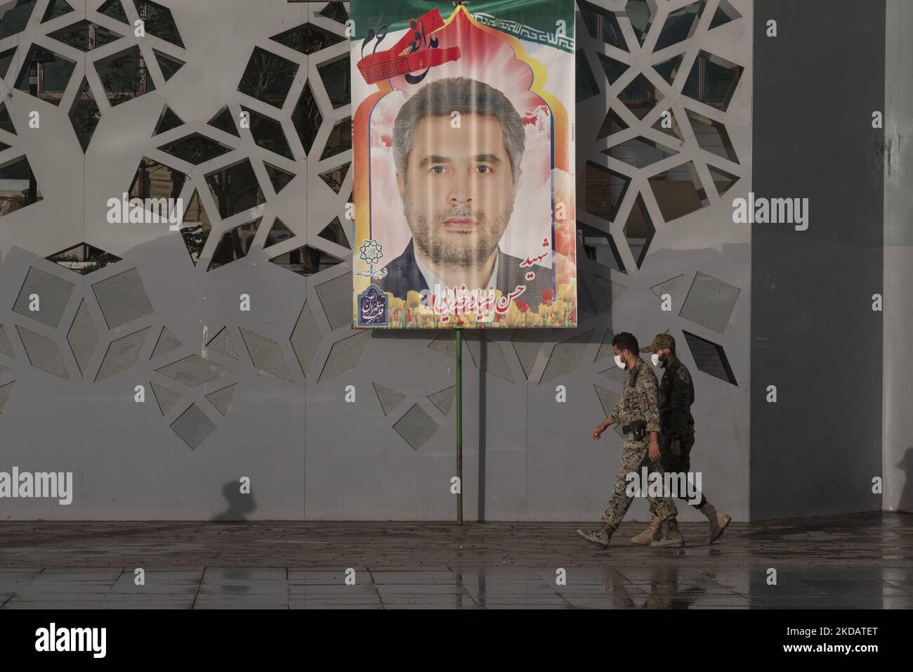 Zwei Militärs der IRGC kommen an einem Porträt des Oberst des Islamischen Revolutionsgarden (IRGC), Sayyad Khodai, während der Beerdigung von Khodai am 24. Mai 2022 im Süden Teherans vorbei. Oberst Sayyad Khodai vom Korps der Islamischen Revolutionsgarde (IRGC) wurde am 22. Mai vor seinem Haus von Motorradmördern in Teheran getötet. (Foto von Morteza Nikoubazl/NurPhoto) Stockfoto