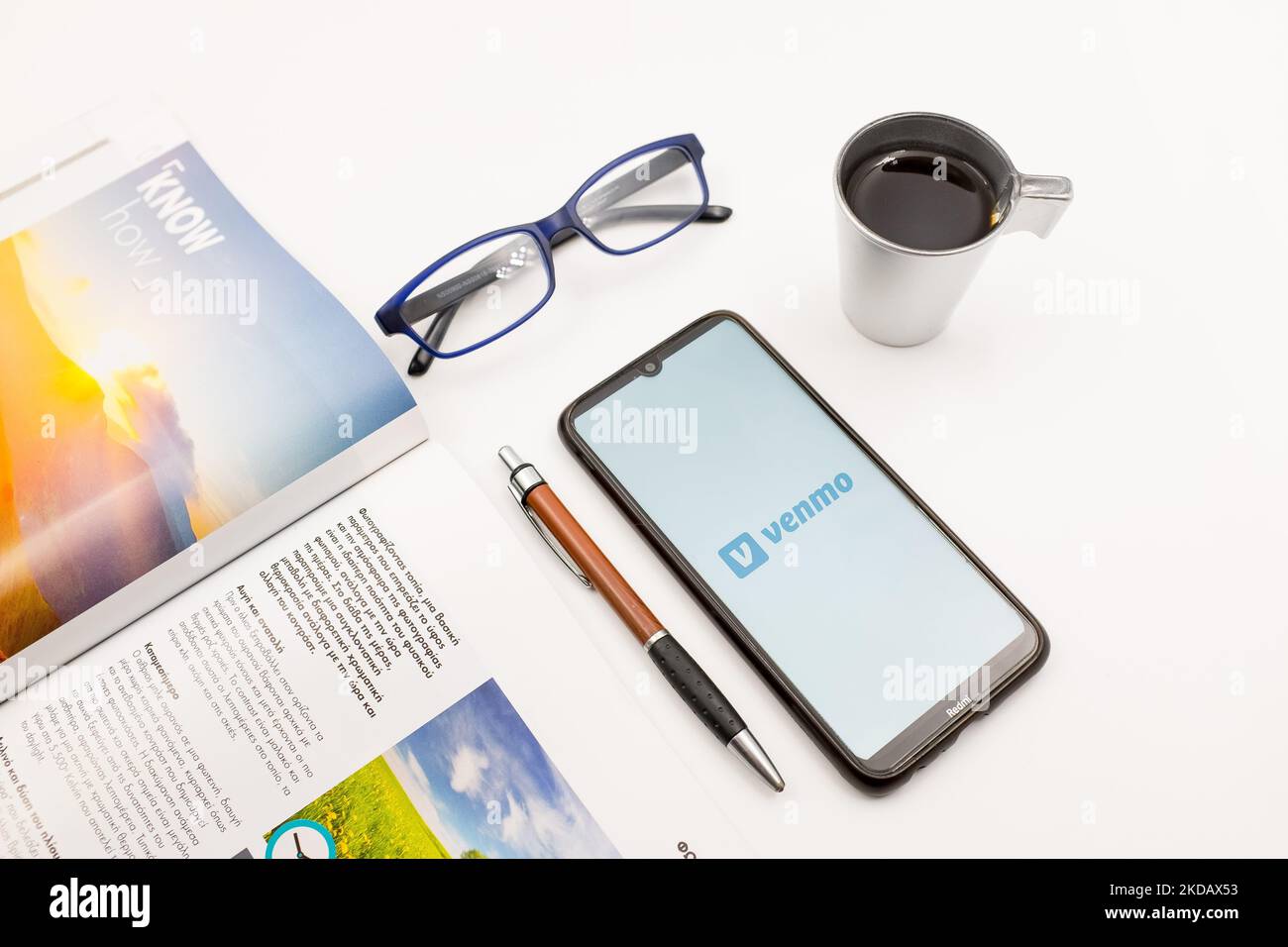 In dieser Fototafel wurde am 25. Mai 2022 ein Venmo-Logo auf einem Smartphone-Bildschirm auf einem Schreibtisch neben einem Café, einem Stift, einer Brille und einer Zeitschrift in Athen, Griechenland, angezeigt. (Foto-Illustration von Nikolas Kokovlis/NurPhoto) Stockfoto