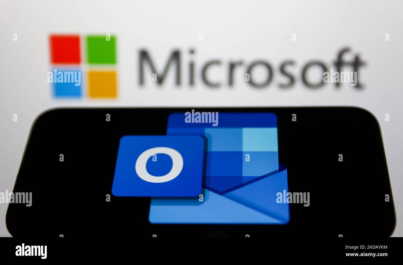 Das Microsoft Outlook-Logo, das auf einem Telefonbildschirm angezeigt wird, und das Microsoft-Logo, das auf einem Bildschirm im Hintergrund angezeigt wird, sind auf diesem Illustrationsfoto zu sehen, das am 26. Mai 2022 in Krakau, Polen, aufgenommen wurde. (Fotoillustration von Jakub Porzycki/NurPhoto) Stockfoto