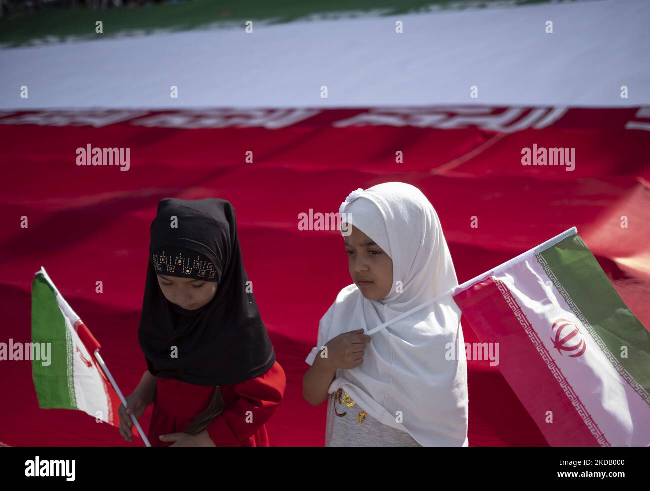Zwei iranische Schulmädchen halten iranische Flaggen in der Hand, um am