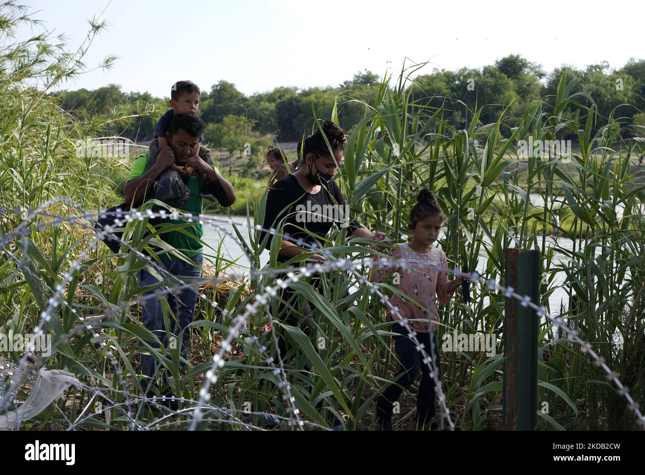 Migranten, die meisten mit Kindern, folgen einem Weg entlang des Konzertsaals, wo sie nach der Überquerung des Rio Grande am 27 2022. Mai im Eagle Pass Texas, USA, von Border Patrol unter Bewachung gestellt werden. Titel 42, das Mandat der Trump-Ära, das Migranten die Einreise in die USA verhindern sollte, Sollte am 23. Mai auslaufen, wurde aber durch eine Klage blockiert, die von mehreren Staaten eingereicht wurde und darauf hinweist, dass der Schritt zum Streik des Gesetzes „die Standards des Verwaltungsverfahrensgesetzes nicht erfüllt“ und dass es keine dauerhafte Lösung für den Umgang mit dem unvermeidlichen Anstieg der Einwanderung gibt. Gegner zum Aufhalten von Stockfoto