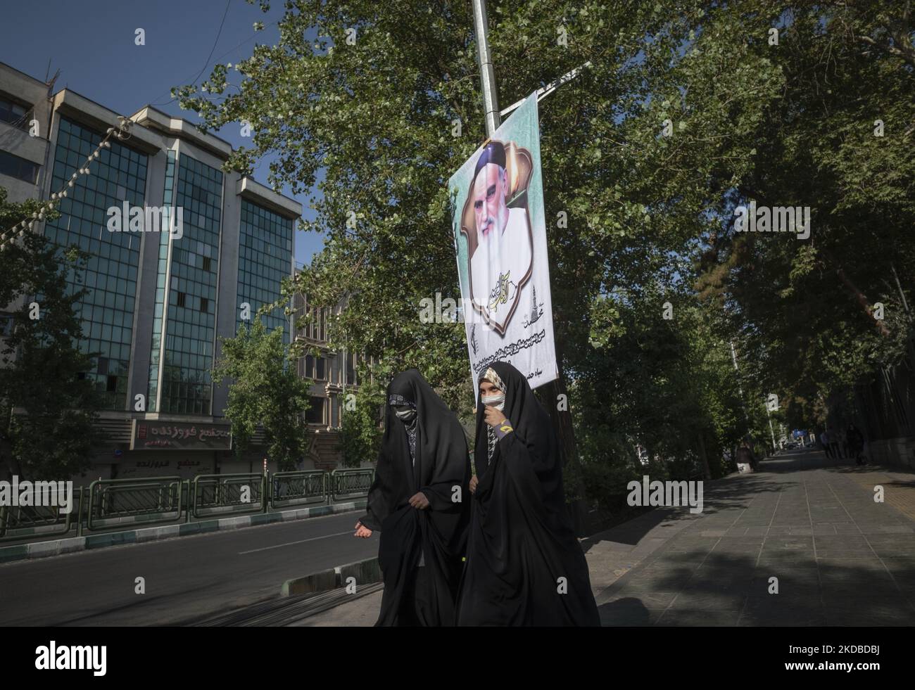 Zwei iranische Studenten der Basiji (Mitglieder der paramilitärischen Streitkräfte der Basij) gehen unter dem Porträt des Gründers der Islamischen Republik, Ayatollah Ruhollah Khomeini, an der Universität von Teheran vorbei, um an einer Kundgebung anlässlich des dreiunddreißigsten Todestages von Ayatollah Khomeini, 3. Juni 2022, teilzunehmen. (Foto von Morteza Nikoubazl/NurPhoto) Stockfoto