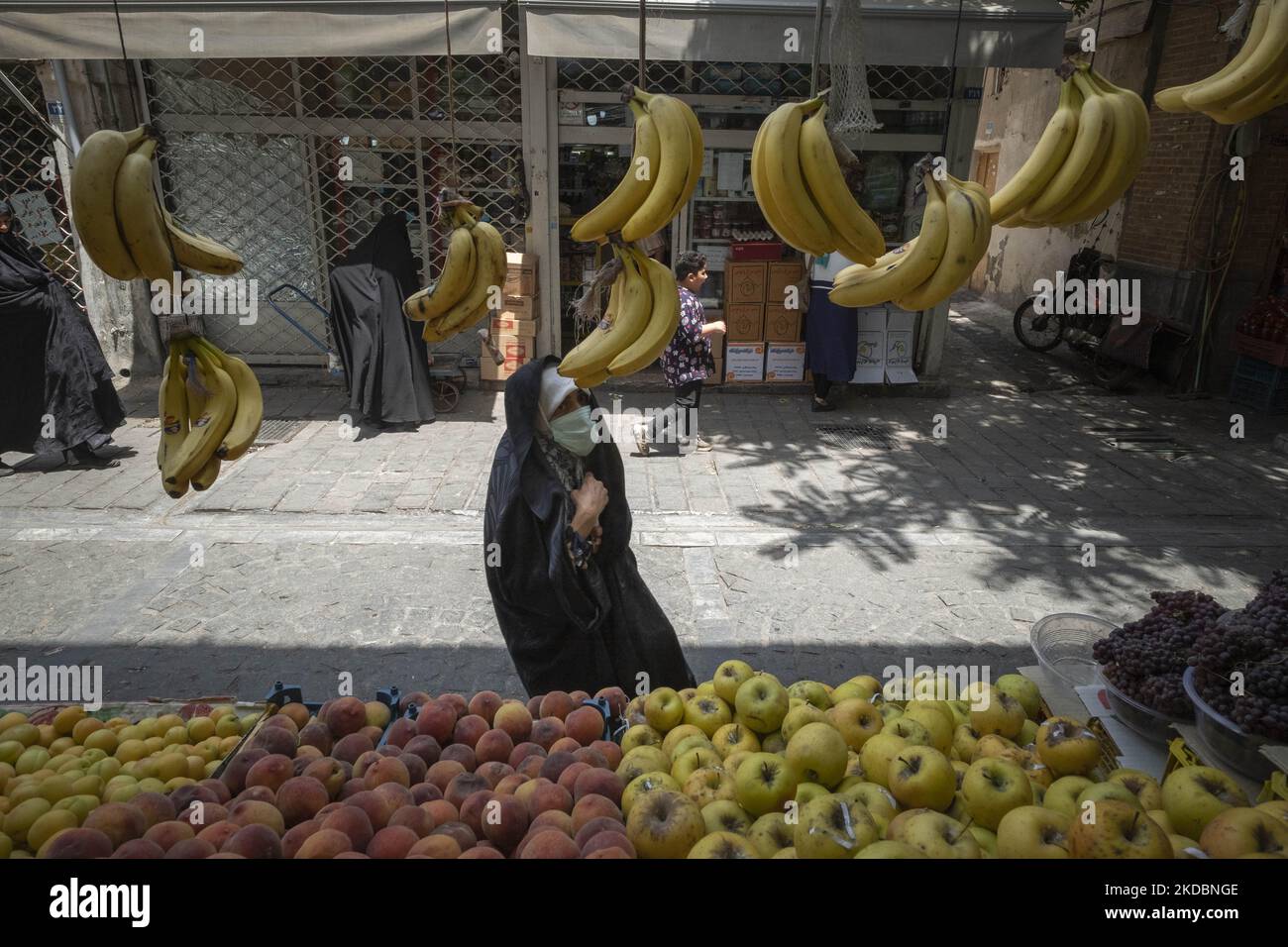 Eine verschleierte Iranerin schaut am 7. Juni 2022 beim Einkaufen auf dem Shapour Bazaar (Markt) im Süden Teherans auf Bananen, die in einem Obstladen aufgehängt wurden. (Foto von Morteza Nikoubazl/NurPhoto) Stockfoto