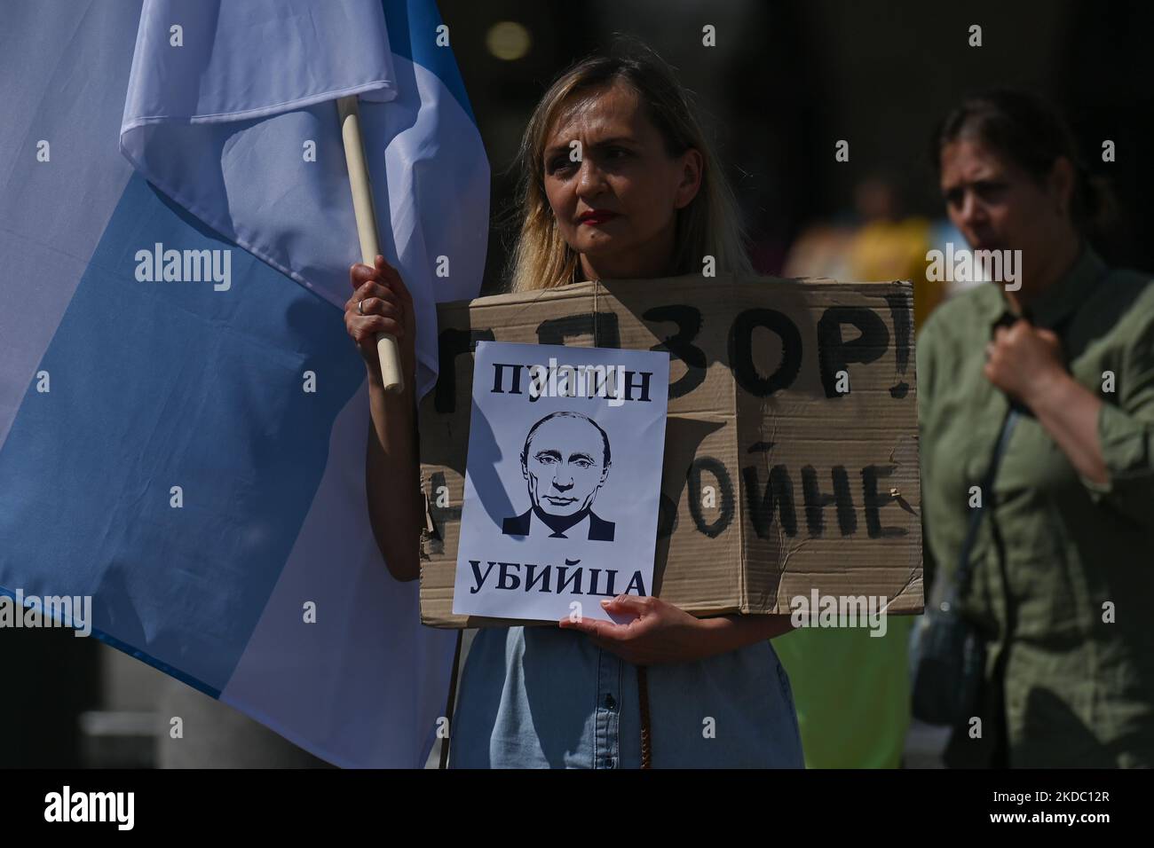 Ein Protestler hält ein Plakat mit den Worten „Putin Killer“ und der weiß-blau-weißen Flagge, Die neue Flagge der russischen Antikriegsbewegung Mitglieder der lokalen russischen Diaspora in Krakau schließen sich der globalen Antikriegsdemonstration aller freien Russen an und protestieren am Adam-Mickiewicz-Denkmal auf dem Hauptplatz in Krakau gegen den Krieg mit der Ukraine. Am Sonntag, den 12. Juni 2022, in Krakau, Polen. (Foto von Artur Widak/NurPhoto) Stockfoto