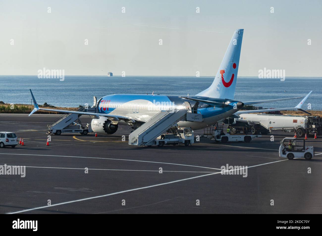 TUI Boeing 737 MAX, gesehen am Flughafen Heraklion auf der Insel Kreta mit einer Fähre im Hintergrund. Kreta ist ein beliebtes mediterranes Sommerziel für Tourismus und Urlaub. TUI war vor kurzem in den Nachrichten wegen Flugverspätungen, Störungen und Annullierungschaos, die hauptsächlich durch den Personalmangel verursacht wurden, der die Luftfahrtindustrie nach der Covid-19-Coronavirus-Pandemiekrise traf. Die TUI Group ist ein deutsches Freizeit-, Reise- und Tourismusunternehmen. TUI Airways verbindet Heraklion mit dem Vereinigten Königreich und Irland, Birmingham, Bournemouth, Bristol, Cardiff, Doncaster/Sheffield, East Midlands, Ex Stockfoto