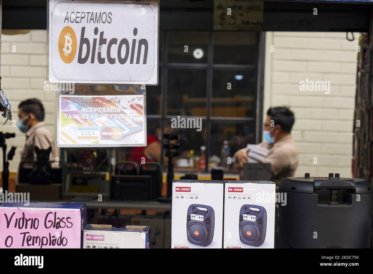 Die Menschen gehen, als ein Schild angezeigt wird, das die Annahme von Bitcoin als Zahlungsmethode am 15. Juni 2022 in San Salvador, El Salvador, ankündigt. Die Regierung von El Salvador hat Verluste von der Hälfte´s $103 Millionen US-Dollar-Investitionen´s´s Bitcoin hinnehmen müssen, da der Bitcoin-Preis auf rund $20.000 US-Dollar fiel. (Foto von Camilo Freedman/NurPhoto) Stockfoto