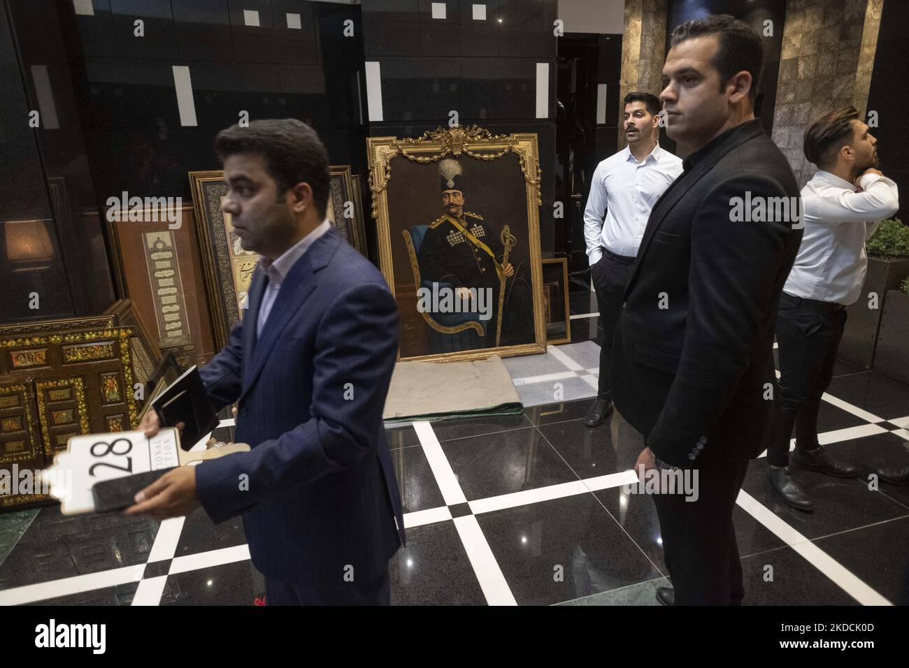 Mitarbeiter und der Besitzer der Melli-Auktion, Ali Ruhani (L), stehen neben einem historischen Gemälde des iranischen Malers Yahyakhan Ghafari, während er sich auf die Teilnahme an der Auktion „Kunst der islamischen und iranischen Welt“ von 7. vorbereitete, Veranstaltet vom Melli (National) Auction House in einem Konferenzzentrum im Norden Teherans am 24. Juni 2022. (Foto von Morteza Nikoubazl/NurPhoto) Stockfoto