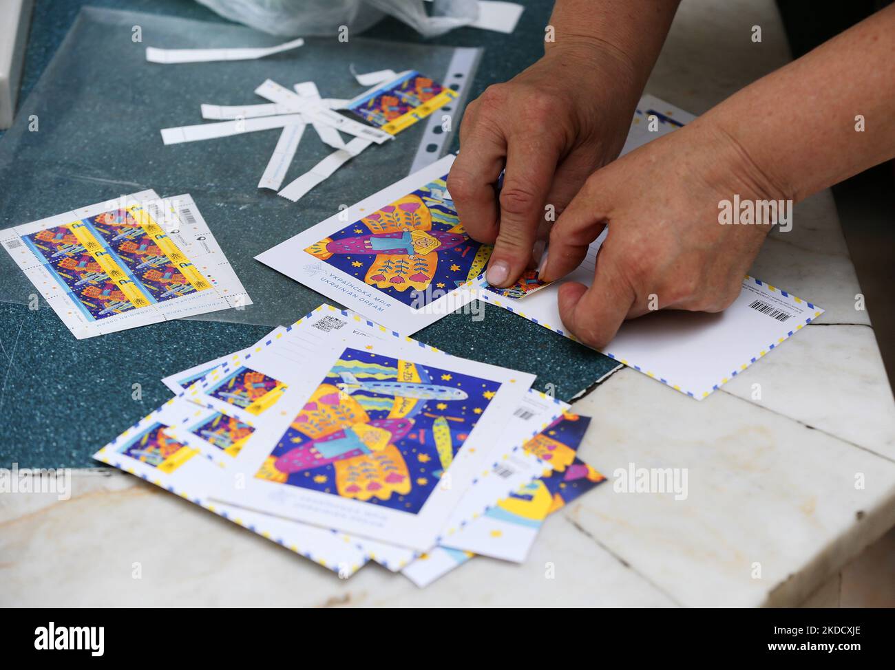 Eine Frau, die eine Briefmarke auf einen Briefumschlag eines neuen Satzes von Postdenkmalmarken namens ''Ukrainischer Traum' klebt, der dem weltweit größten Flugzeug der Ukraine AN-225 'Mriya' ('Traum') gewidmet ist, während der russischen Invasion in der Ukraine, im Hauptpostamt in Odesa, Ukraine, am 28. Juni 2022. Die Briefmarke symbolisiert den Willen zum Sieg unseres Landes, der nicht gebrochen werden kann, kommentiert in Ukrposchta. Der Autor der Skizzen für die Briefmarke „Ukrainischer Traum“ war eine Zeichnung der elfjährigen Sofia Kravchuk aus der Region Wolyn, in der das größte Flugzeug zu den Sternen fliegt. Die Circu Stockfoto