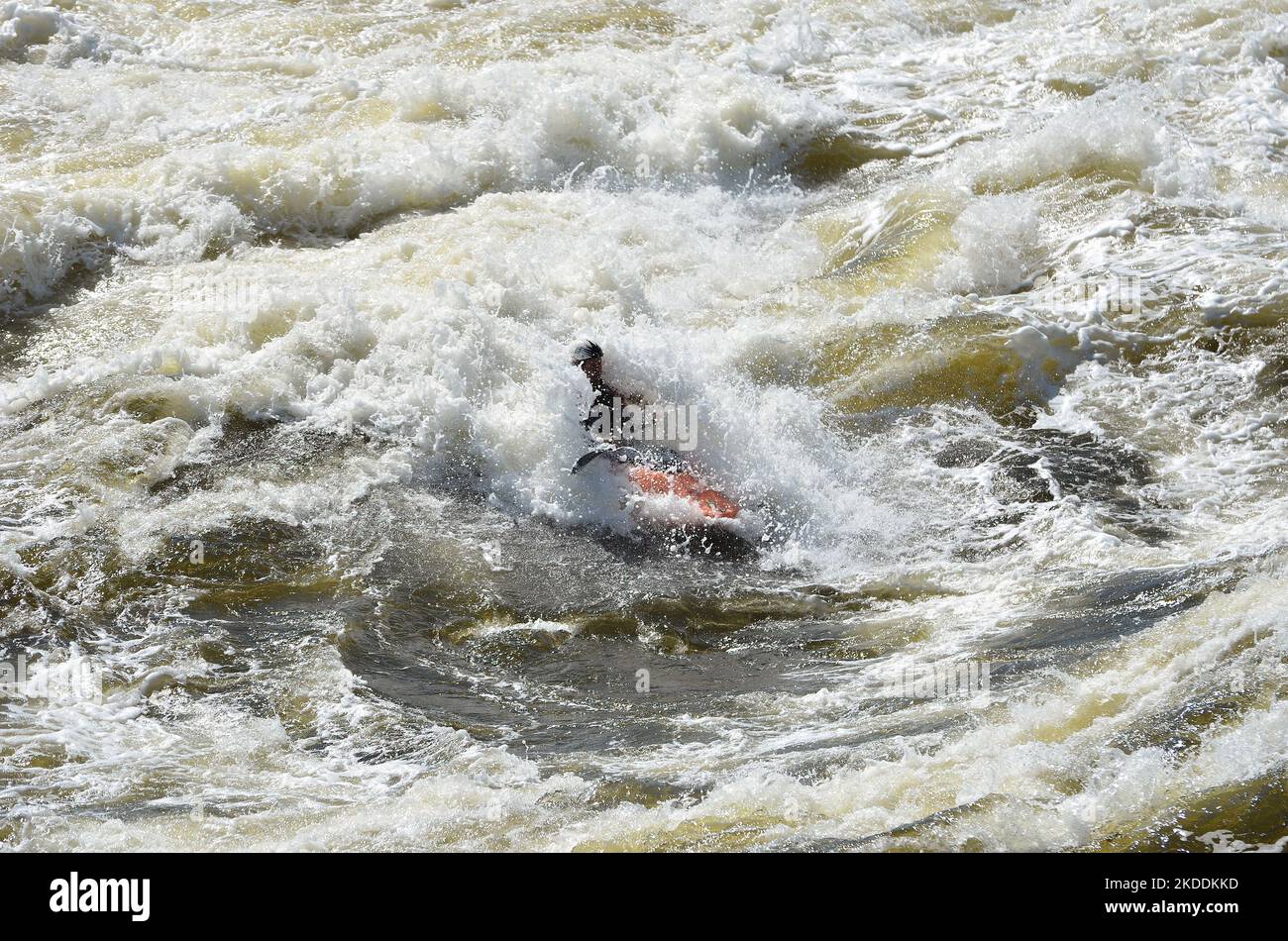 Kajakfahren in sehr rauen Stromschnellen. Der Fluss ist heftig mit vielen turbulenten Wellen und Spray. Das Gesicht der Person im Kajak ist nicht erkennbar. Stockfoto