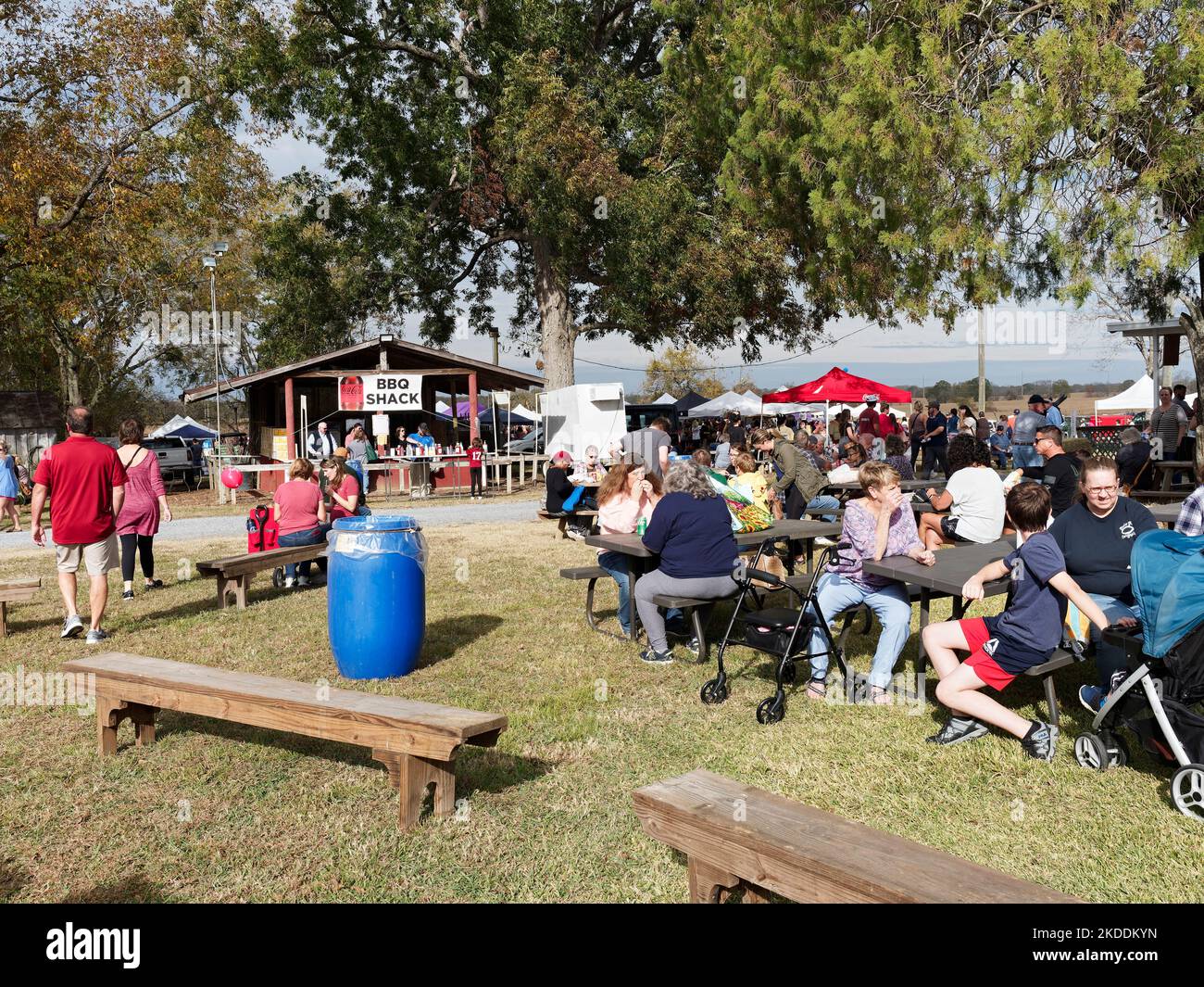 Familien und Männer, Frauen und Kinder, die an Picknicktischen im Freien sitzen, essen auf einem lokalen Kunsthandwerksmarkt in Pike Road Alabama, USA. Stockfoto