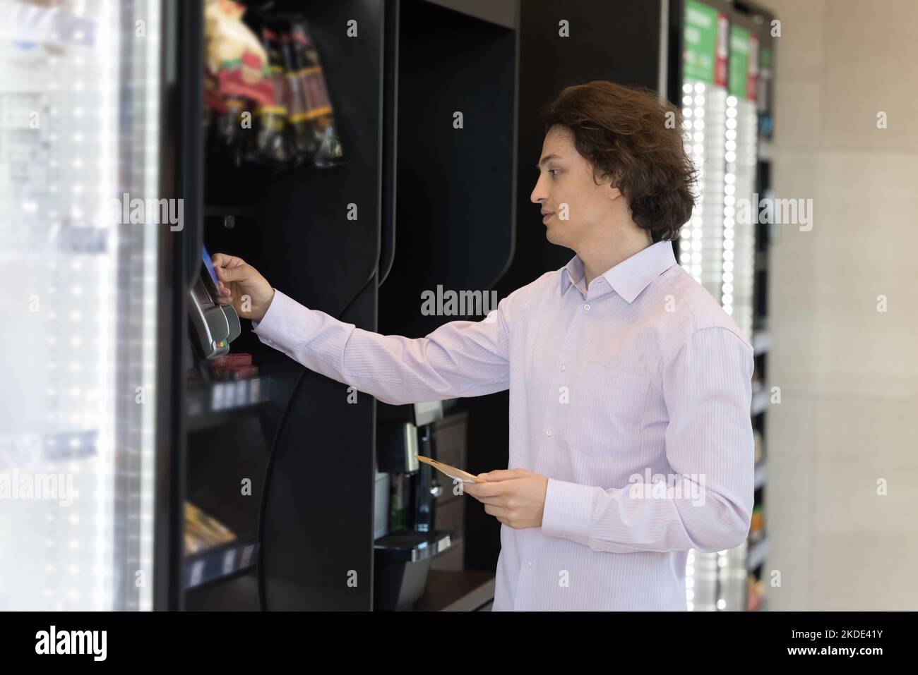 Der Mann benutzt eine Karte, die für den Snack zahlt, der im Automaten gekauft wurde Stockfoto